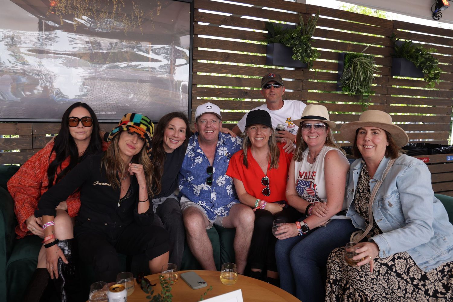 A group of people gathered together at a casual outdoor dining venue with wooden slat walls.