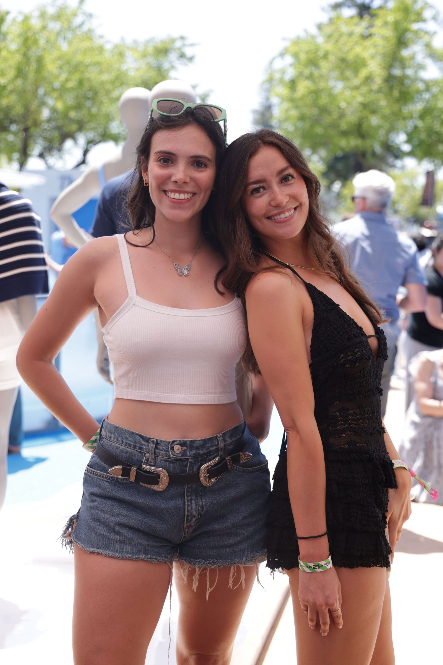 Friends posing together at an outdoor summer event wearing casual outfits.