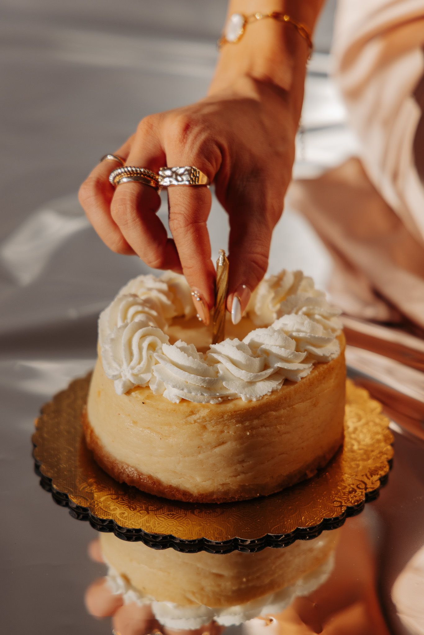 Close-up sequence of hands decorating a brown frosted cake on a black cake board with white whipped cream details.