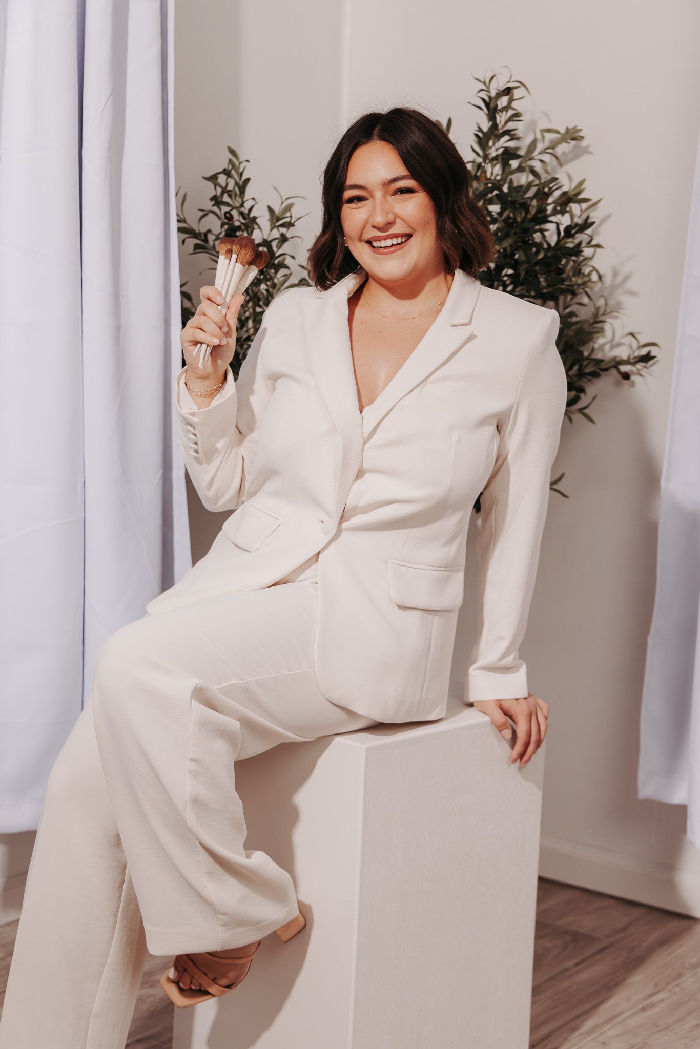 Collage of a woman wearing a chic white suit poses playfully against a white curtained background in a modern setting.