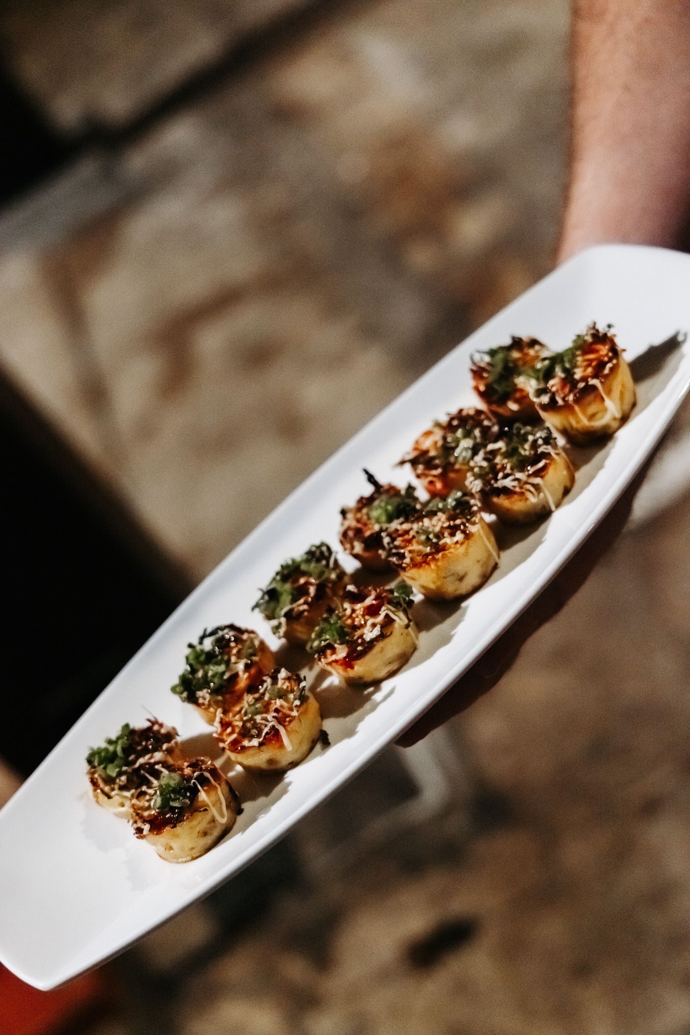 Elegant appetizers garnished with microgreens served on a white rectangular plate.