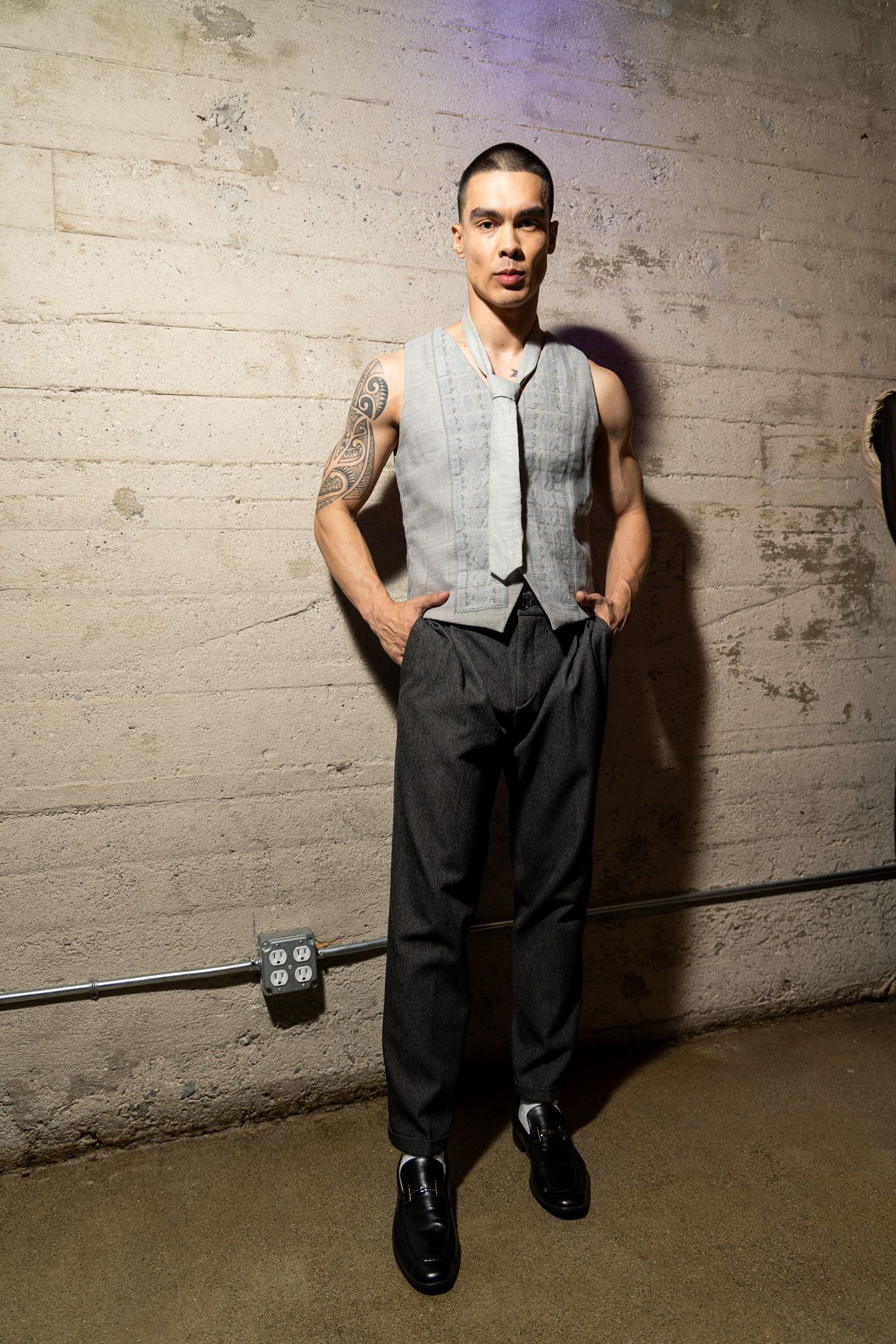 A figure in a gray vest and black pants poses against a concrete wall in a series of dynamic dance movements.