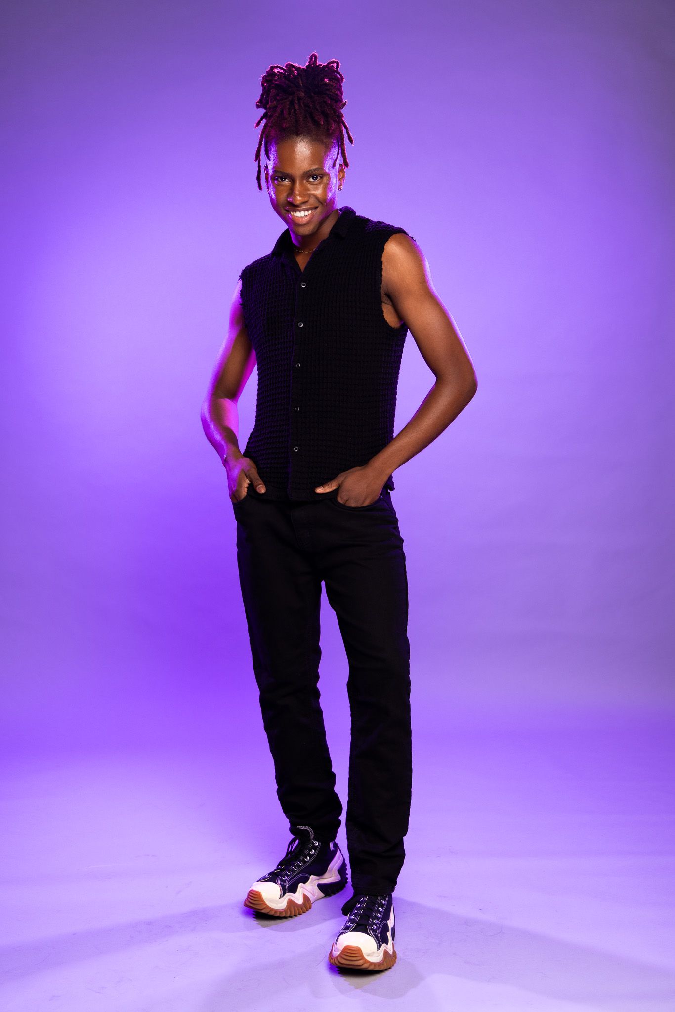 Figure in black outfit dances against purple backdrop showing dynamic movement and style.