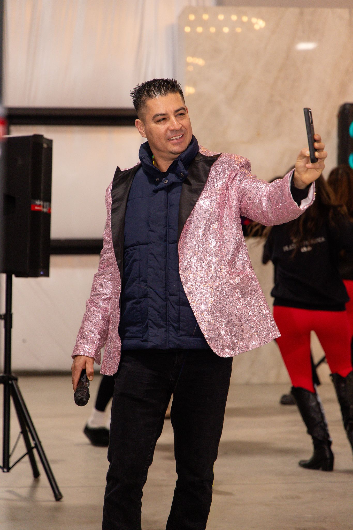 People dancing in a studio space with one wearing a sparkly pink top and navy jacket.