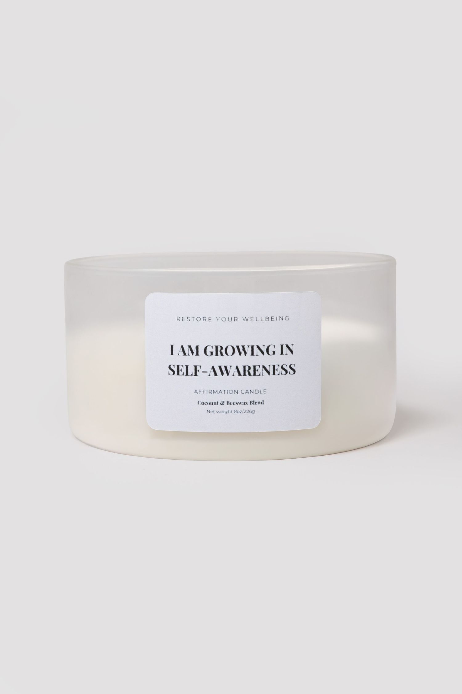 Frosted white ceramic affirmation candle reading I Am Growing In Self-Awareness, coconut beeswax blend.