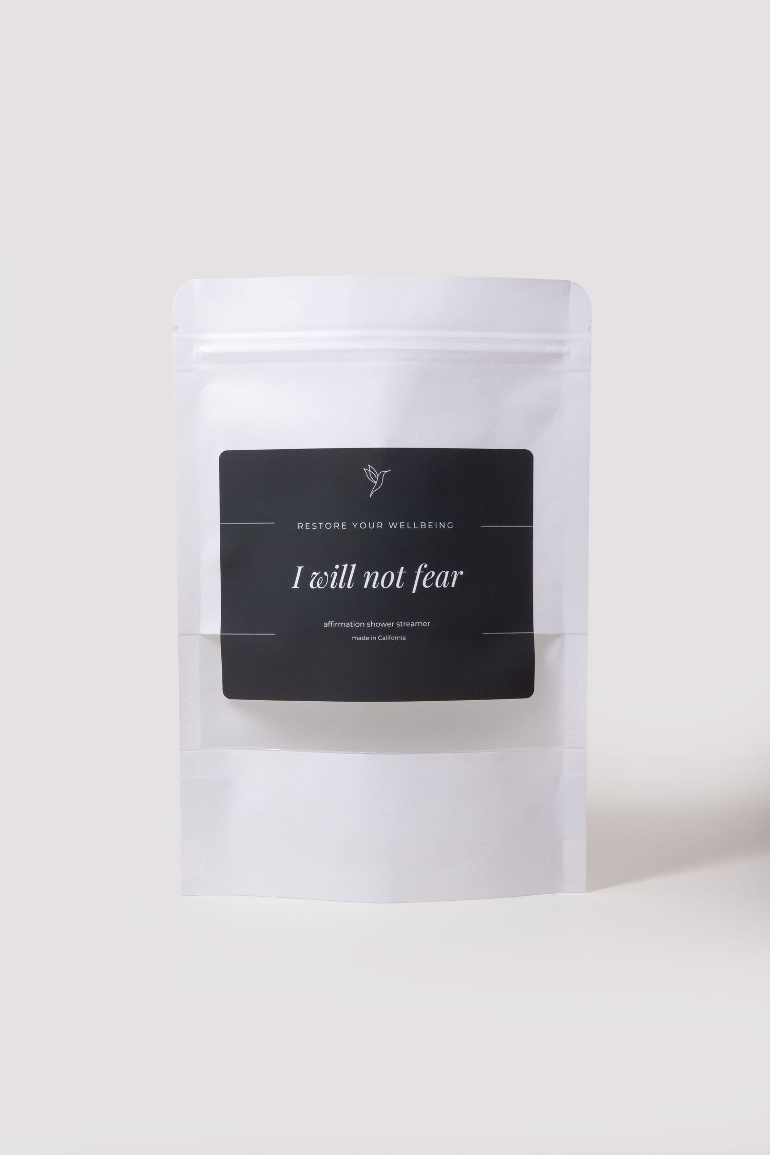 White pouch of Restore Your Wellbeing affirmation shower steamer labeled I Will Not Fear on black label.