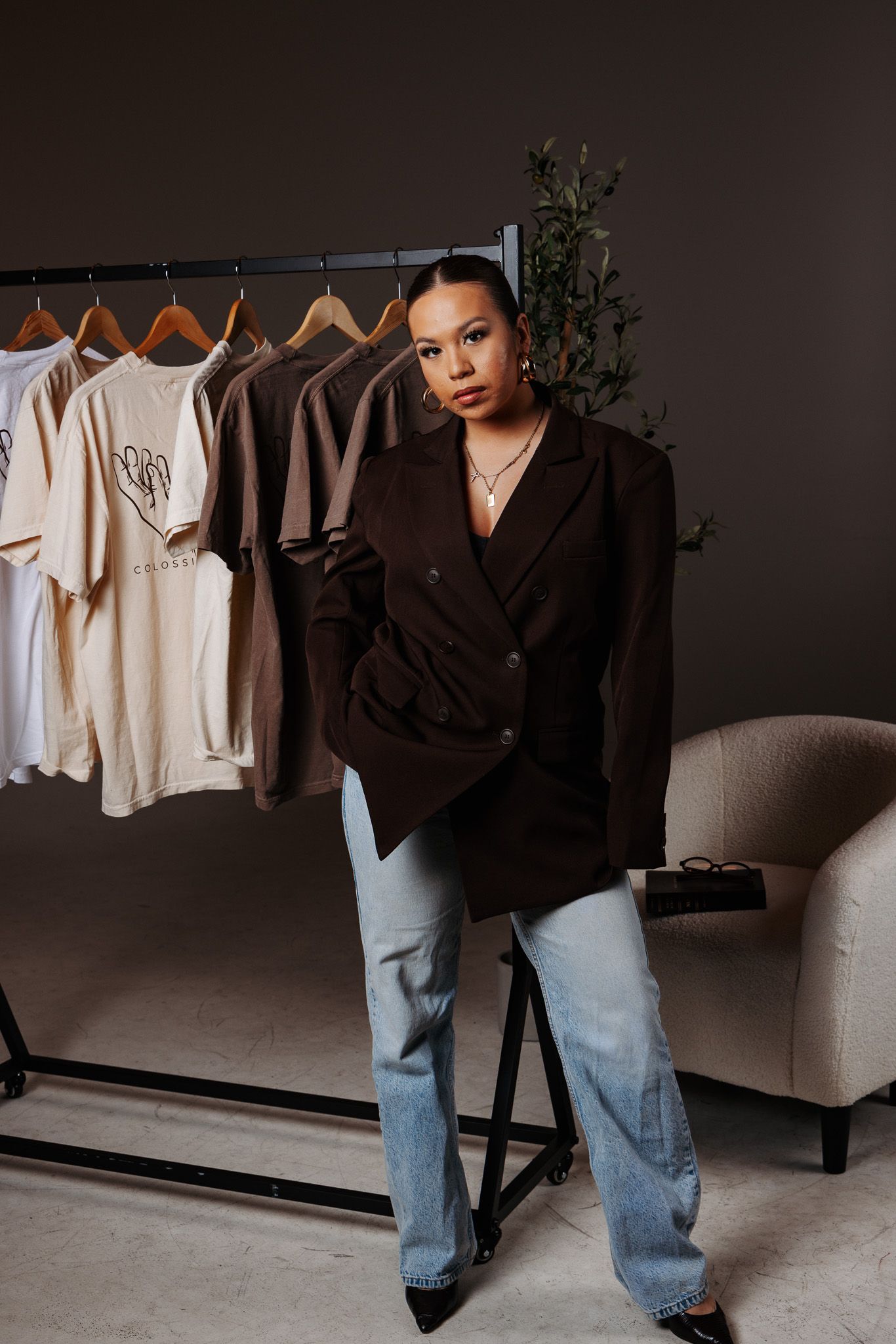 A minimalist fashion scene with light colored clothing on hangers against a dark wall contrasts with blue denim.