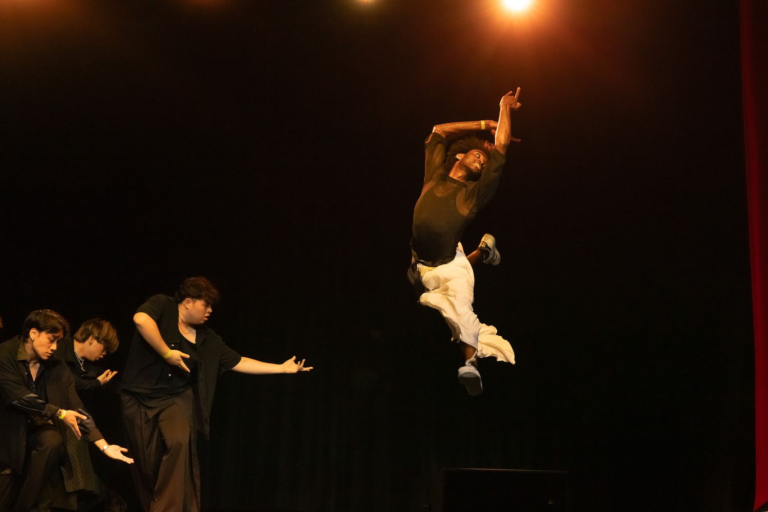 Performance dancers create a dramatic scene on a dark stage with dramatic lighting and expressive movements.