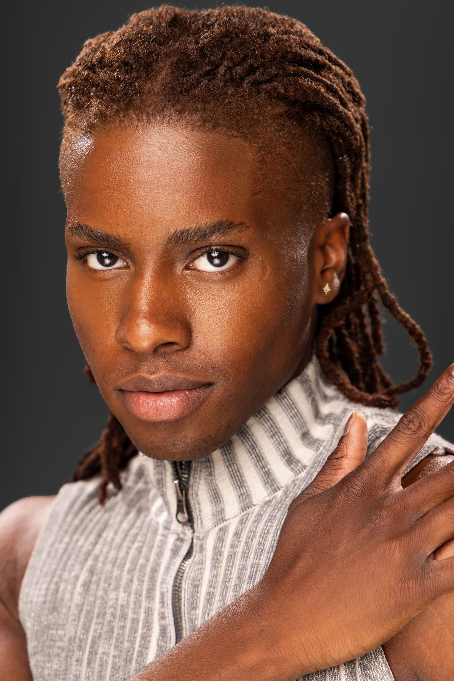 Close-up portrait wearing a gray turtleneck sweater against a dark background.