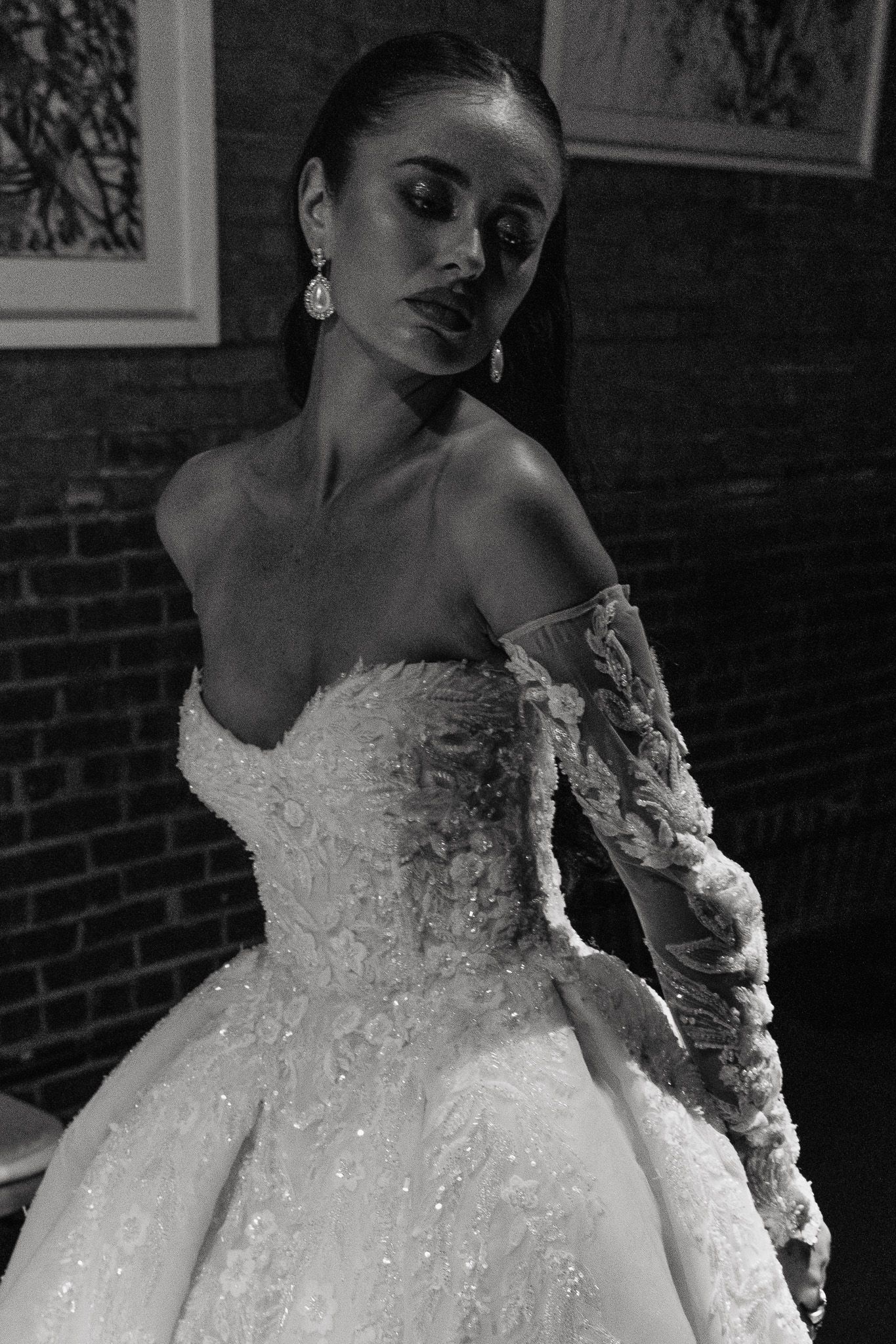 Black and white bridal portraits showing an elegant off-shoulder wedding gown with intricate lace sleeves and beading.