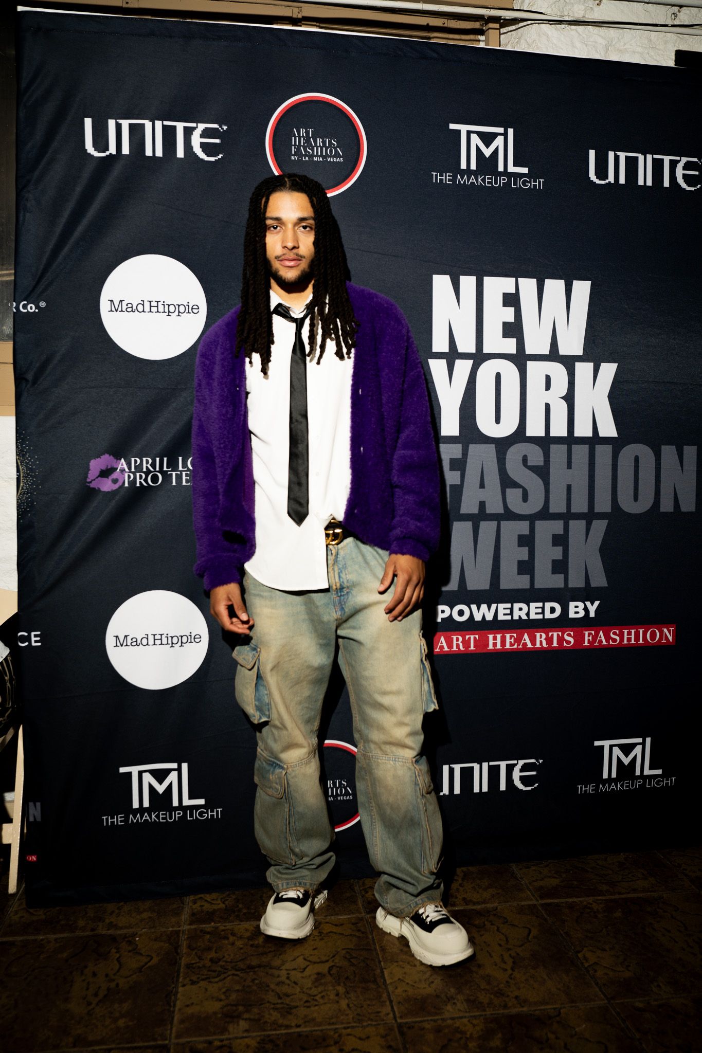 Fashion event backdrop displaying New York Fashion Week branding with purple and black color scheme.