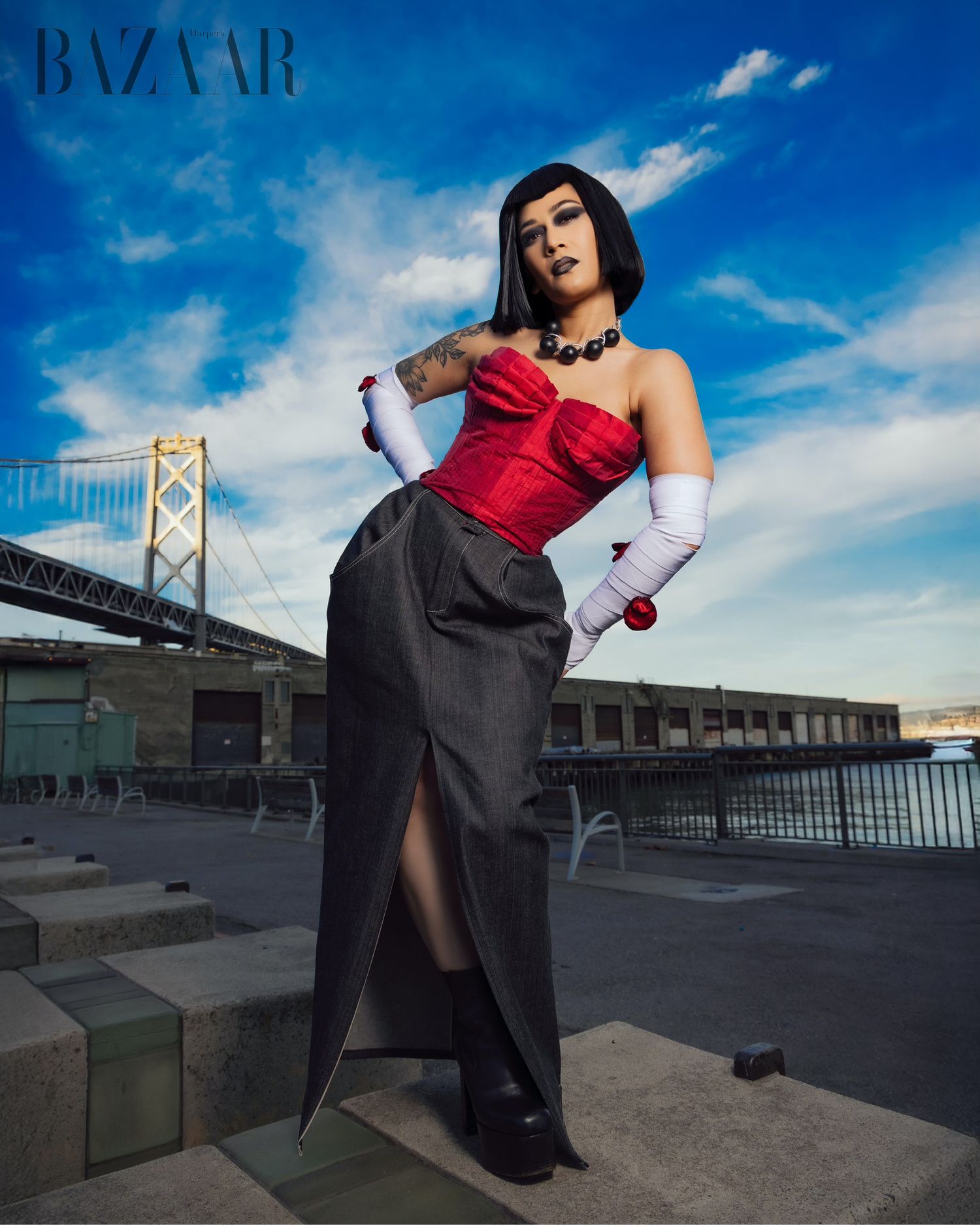 Fashion photoshoot featuring dramatic poses on urban rooftop with bridge and blue sky backdrop.