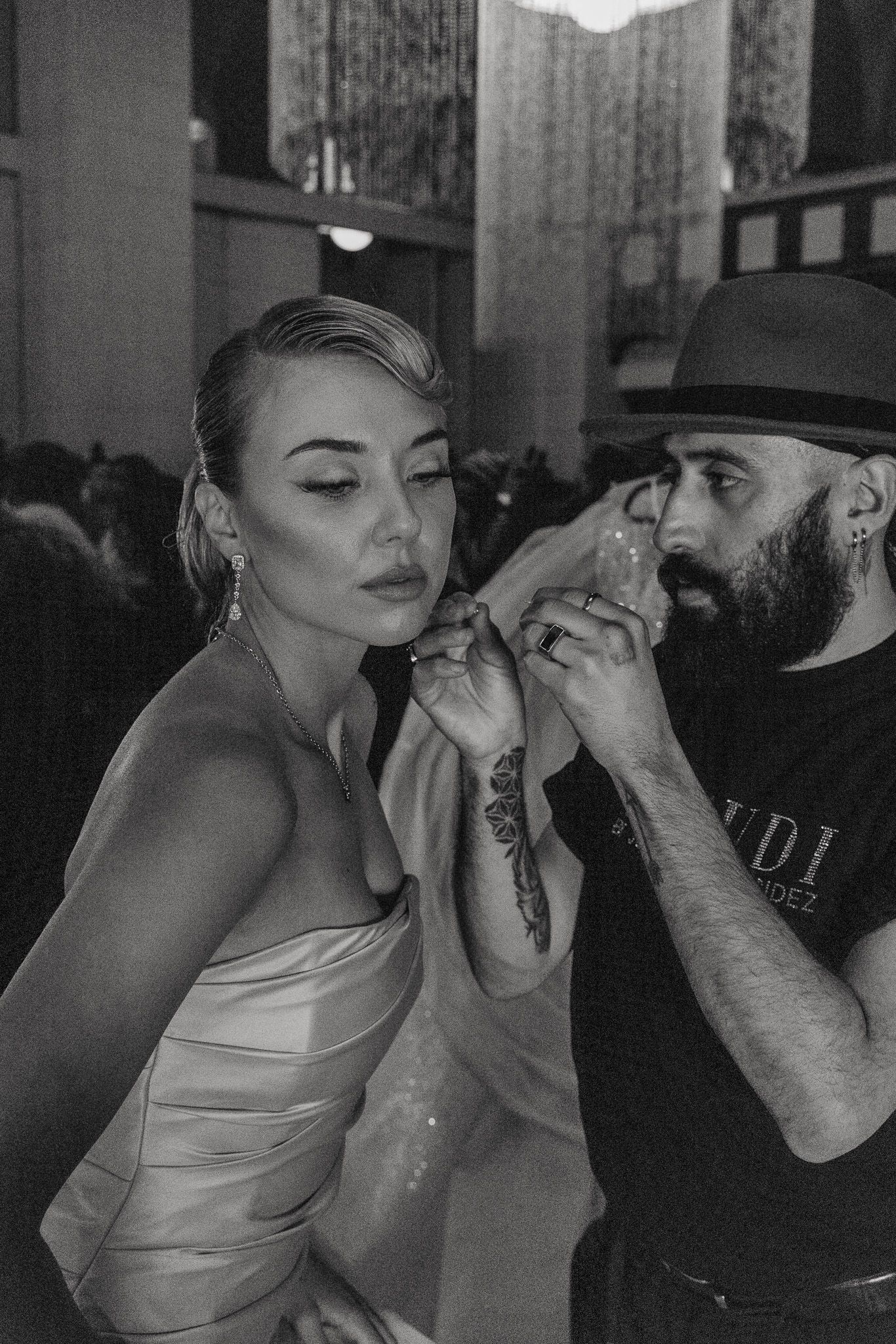 Black and white photo of backstage makeup application at a fashion show.
