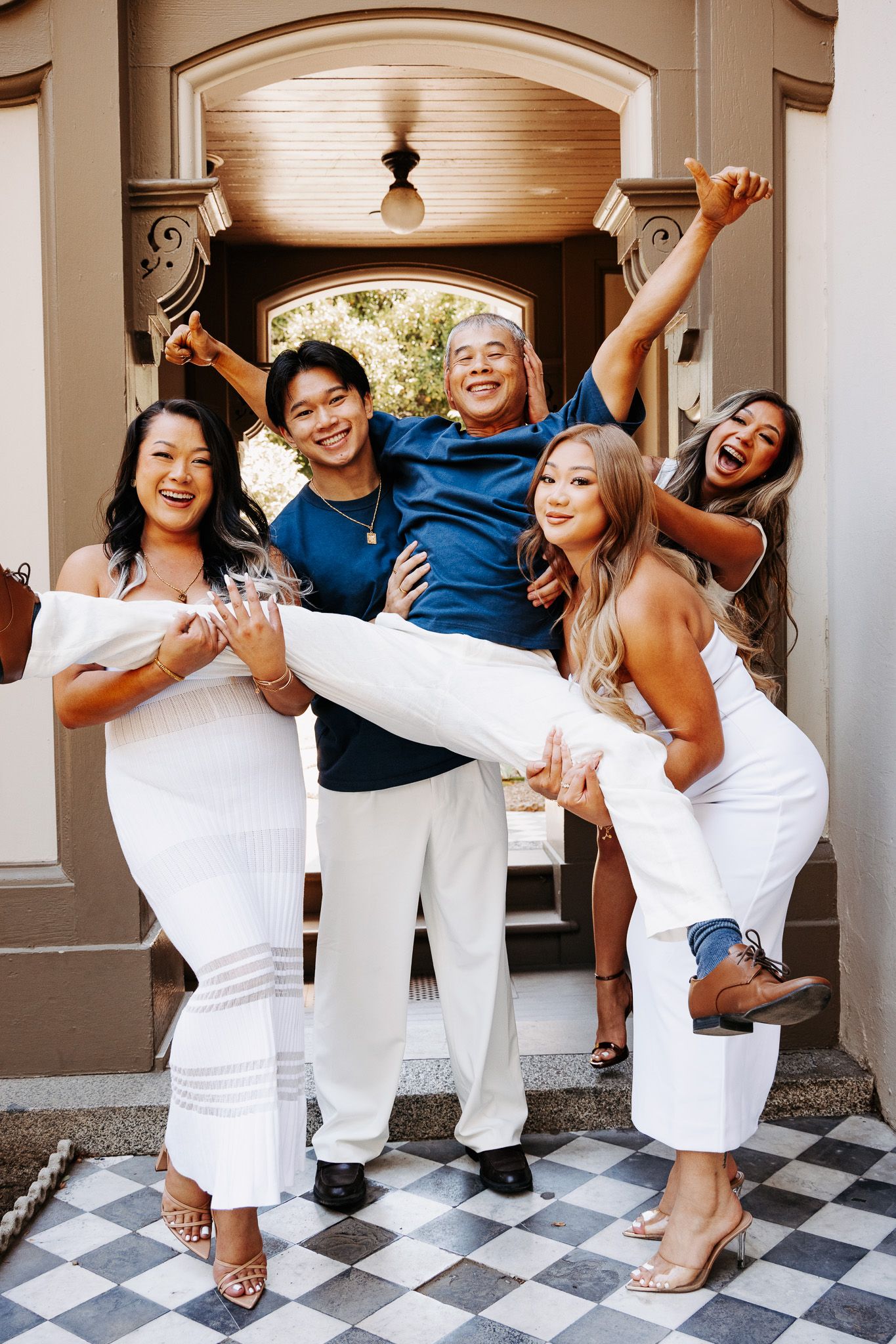 A group in coordinated white and navy outfits poses playfully on a checkered floor for a fun photo series.