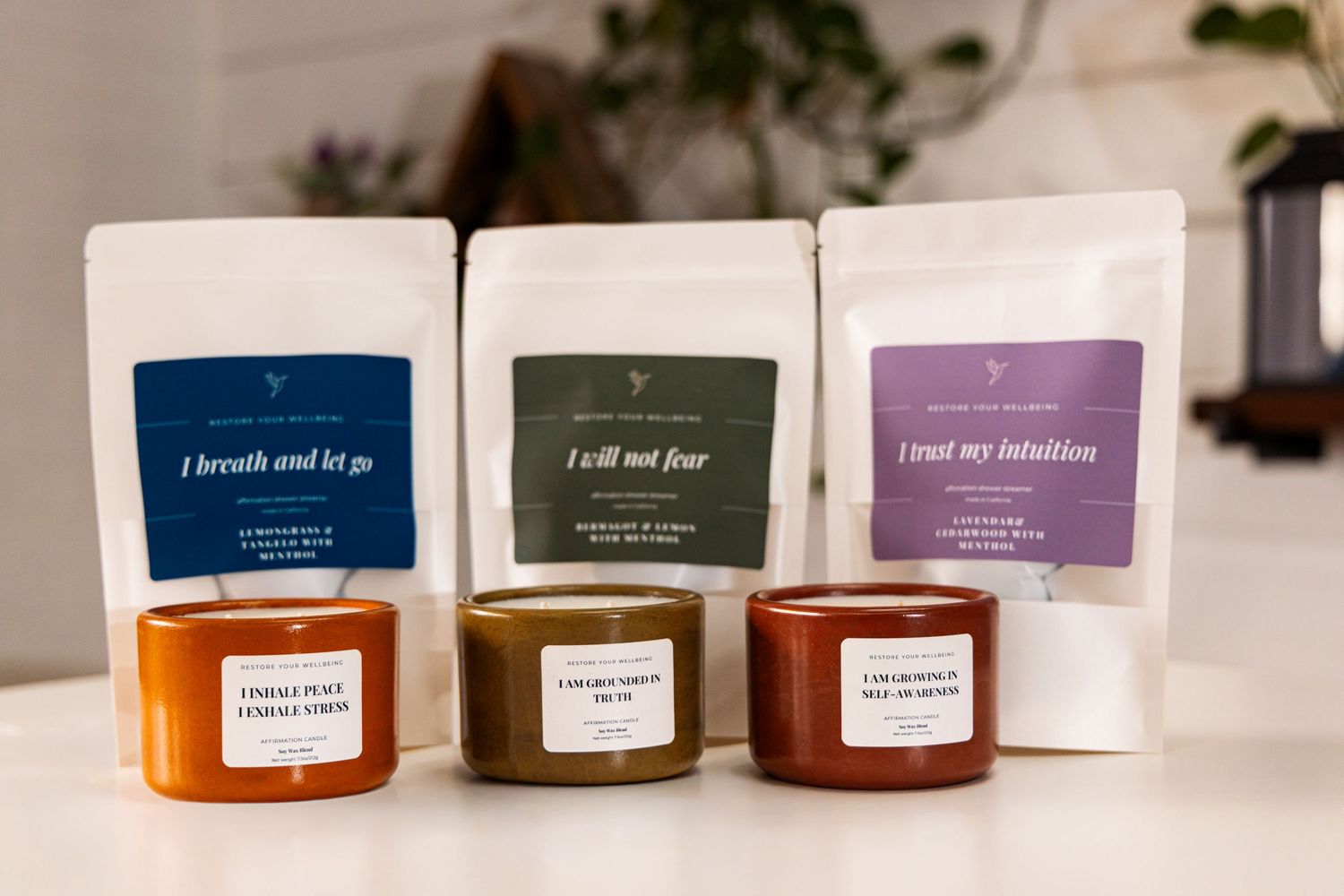 Multiple scented candles in amber and clear glass containers displayed with blue and purple affirmation cards.