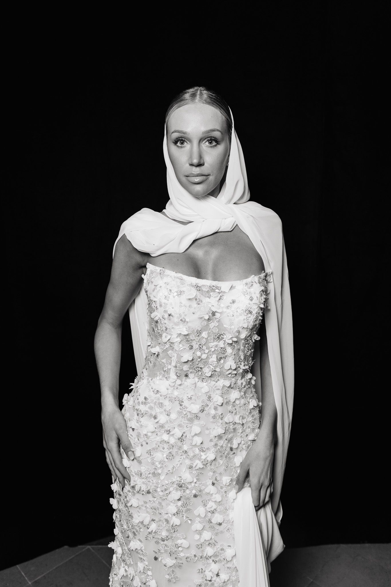 Elegant bridal fashion sequence featuring a white dress adorned with floral appliques and flowing veil against black backdrop.