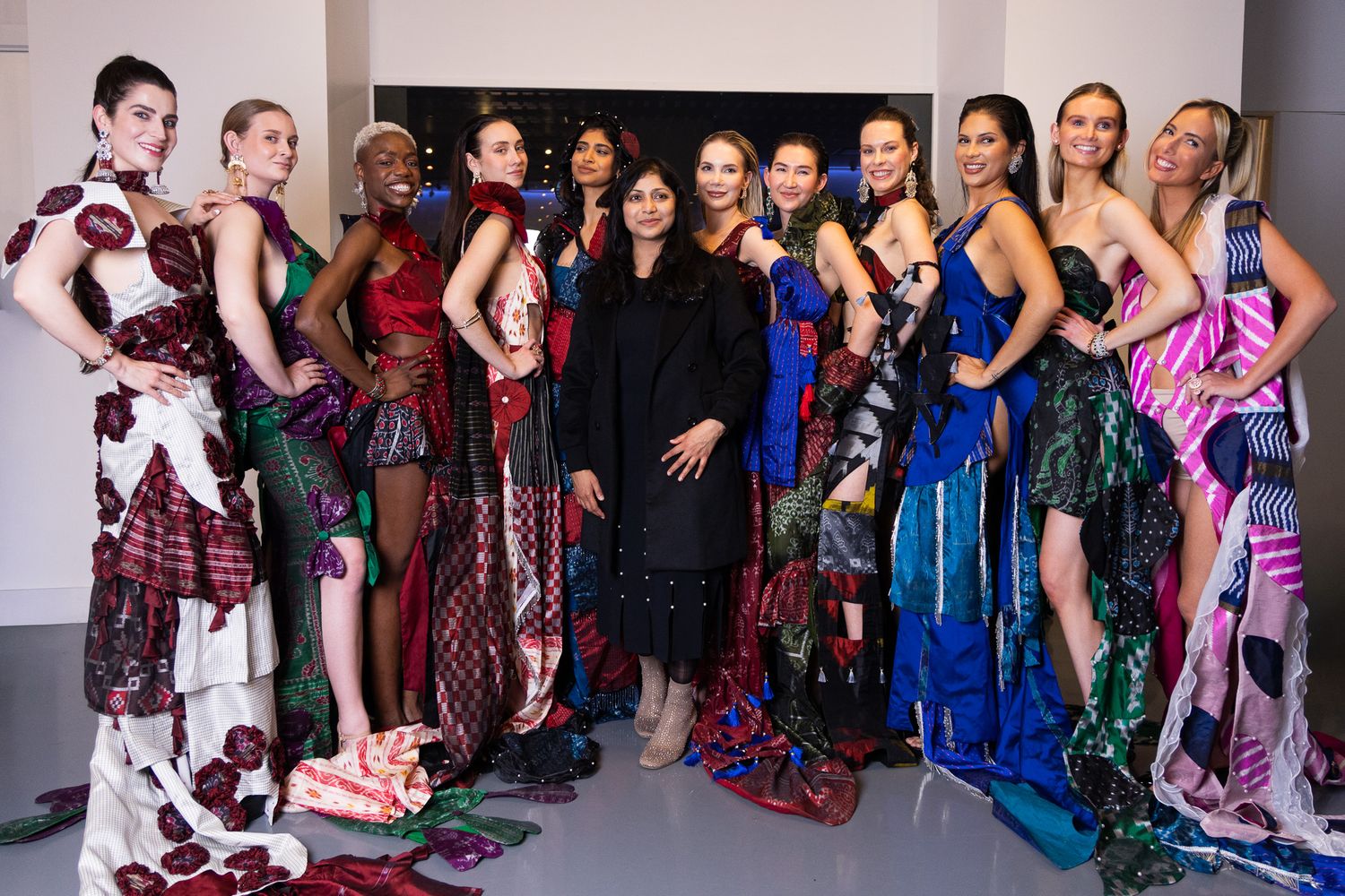 Group photo of fashion models and designers posing together at a runway show event.