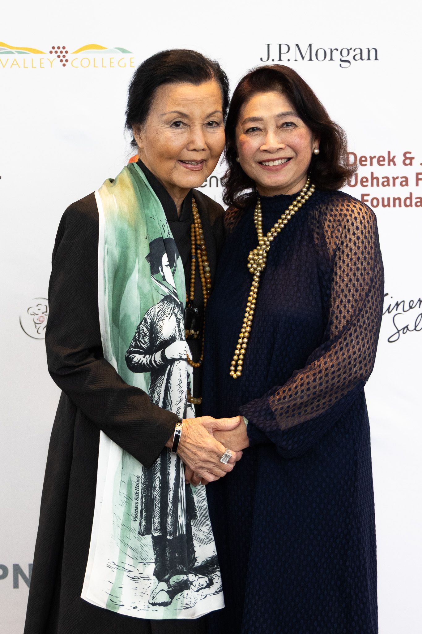 Two people pose together at a formal event with JP Morgan branding visible in the background.