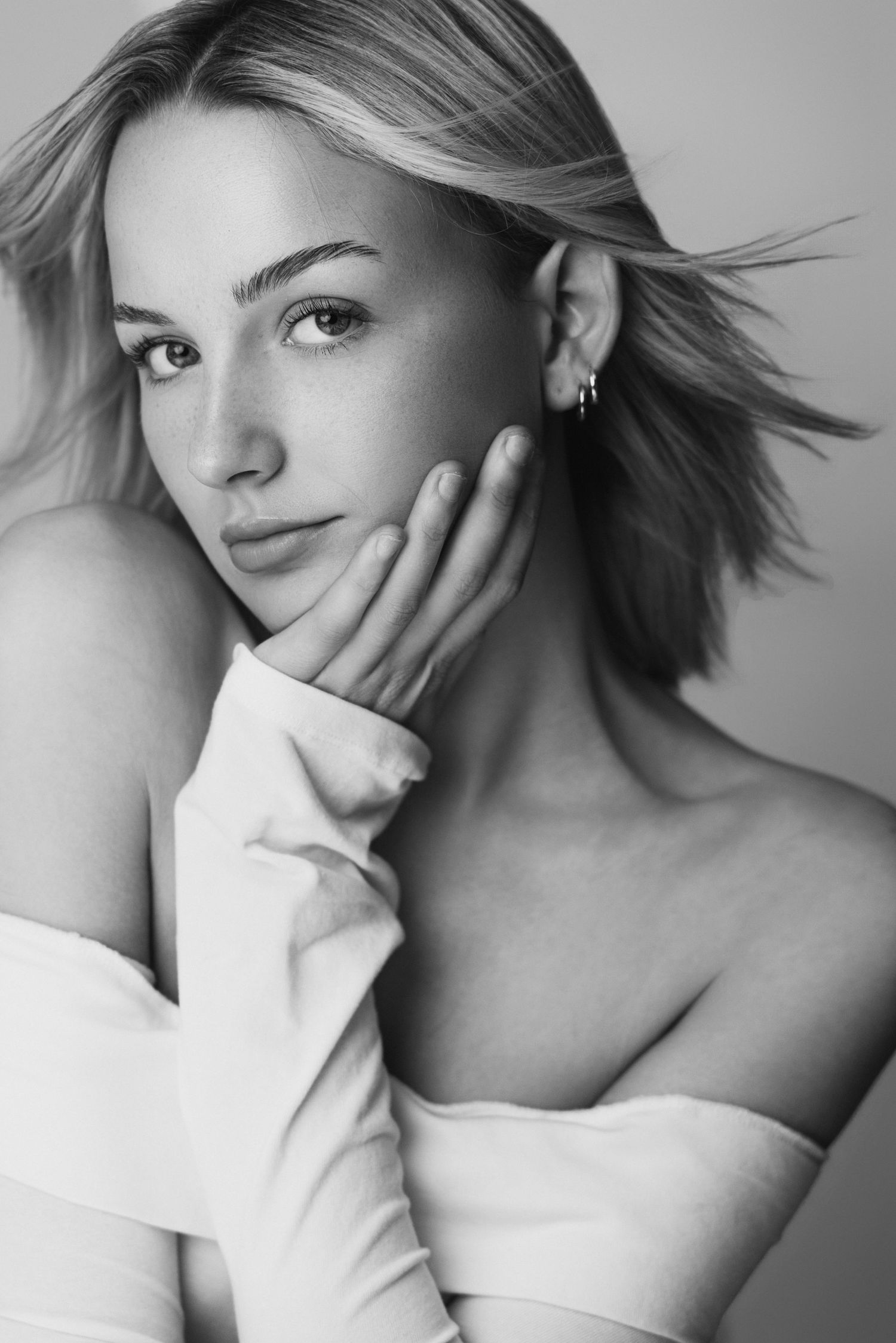 Black and white artistic portrait series showing different poses and expressions with windswept hair against white backdrop.