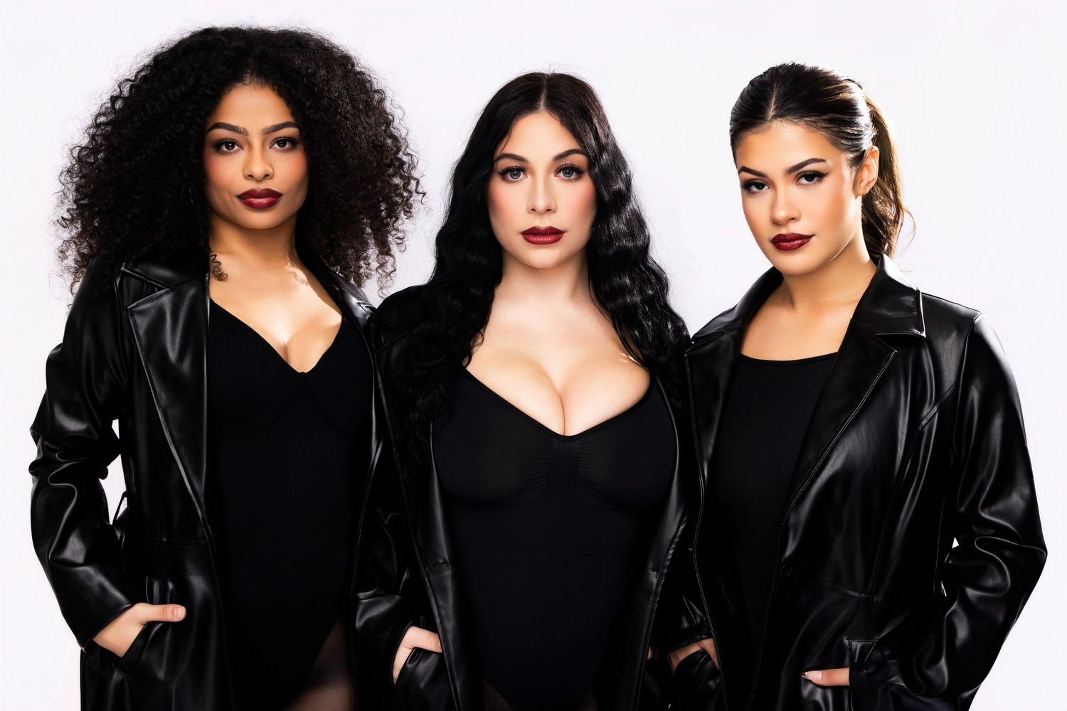A group of women in black leather jackets and dark clothing pose together in a stylish fashion photo.