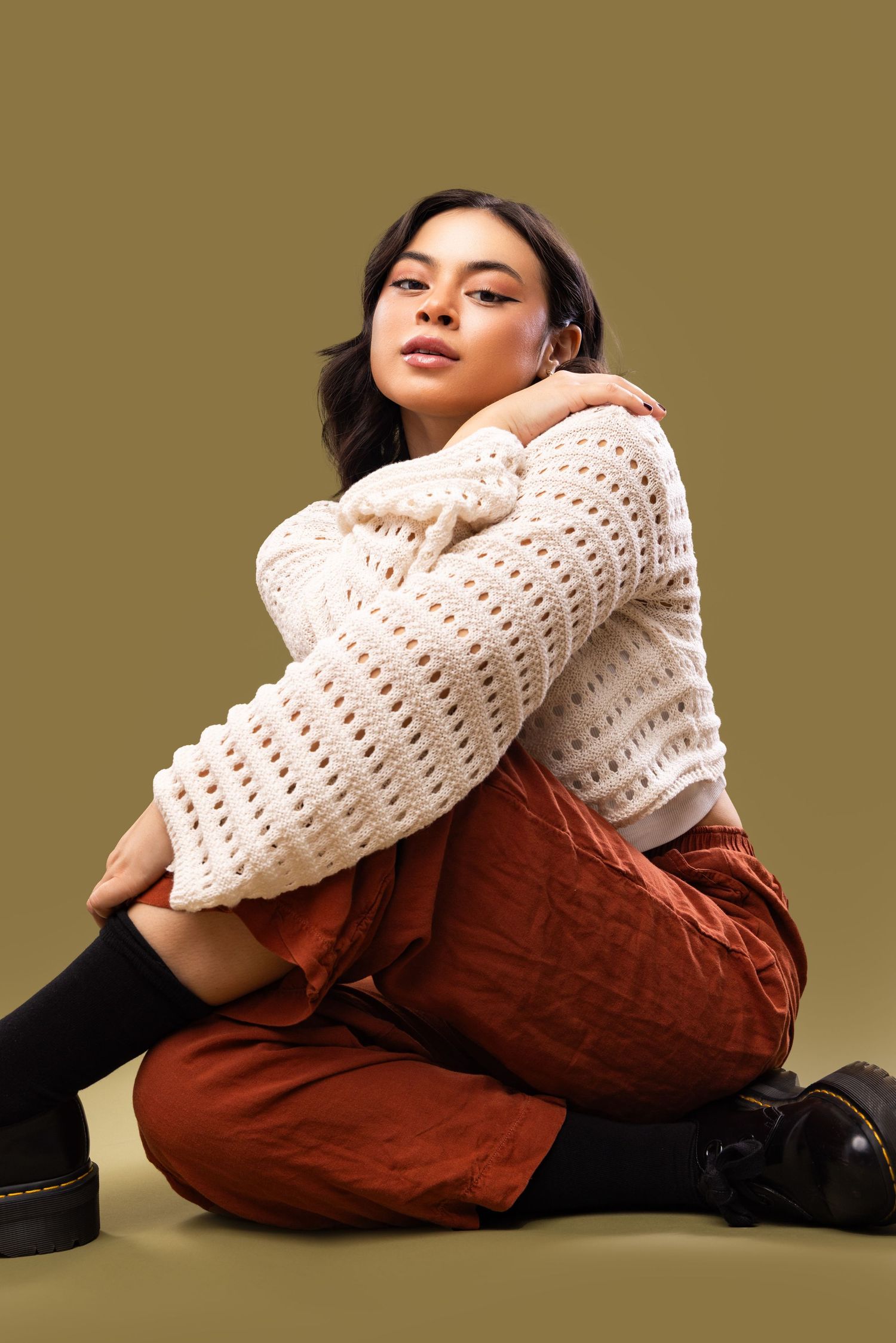 A series of artistic poses showcasing a white knit sweater with brown corduroy pants against a neutral backdrop.