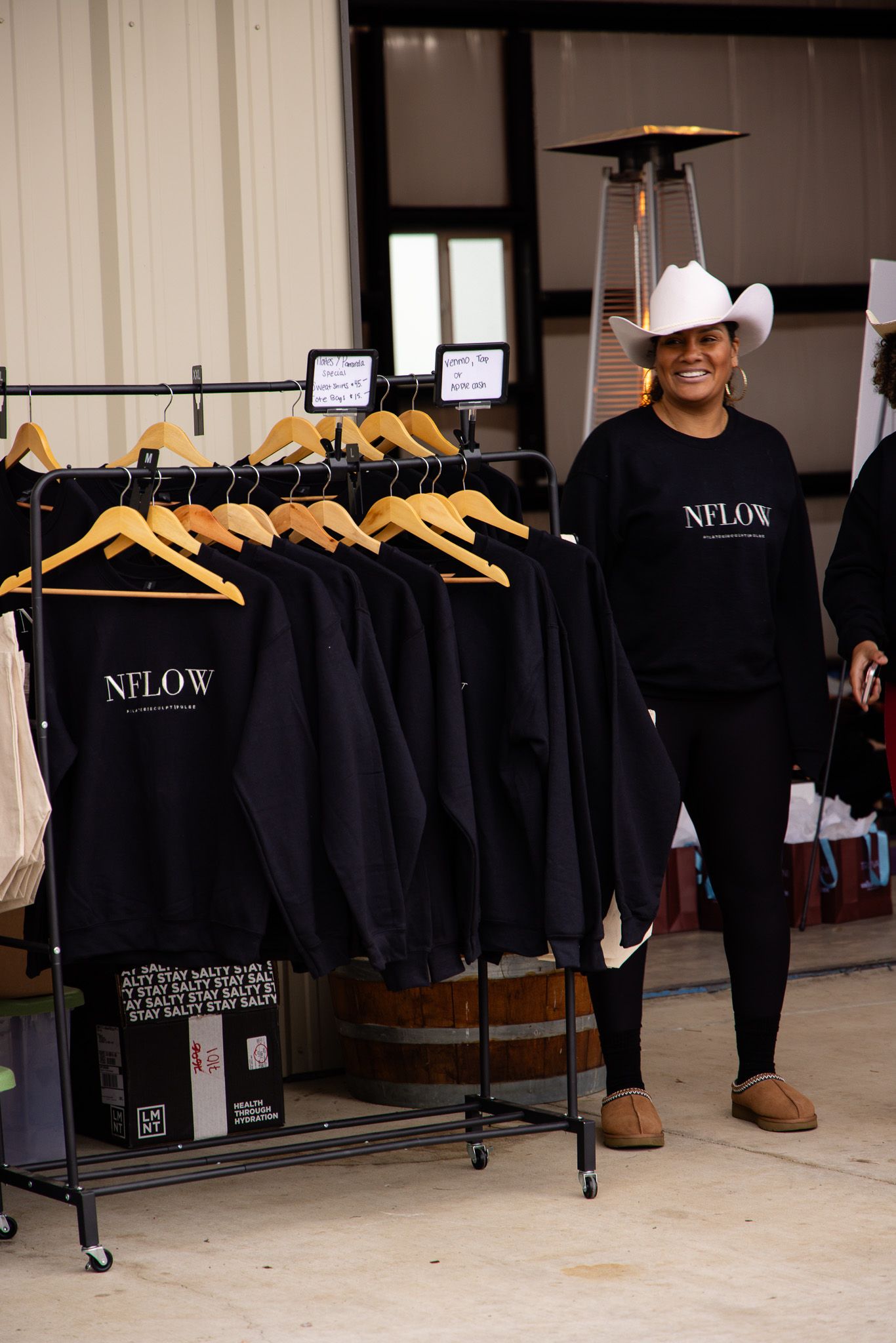 Black clothing items labeled 'NFLOW' hanging on retail display racks.