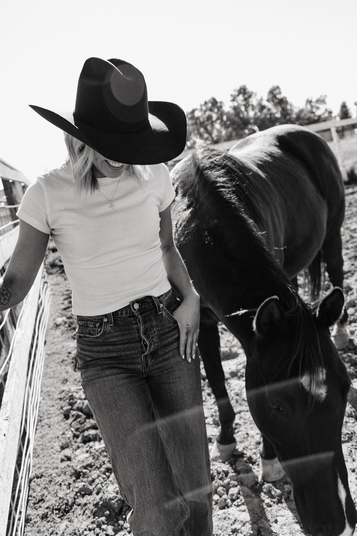 Several people in jeans and casual attire bend down to work in an agricultural field setting, shown in black and white.