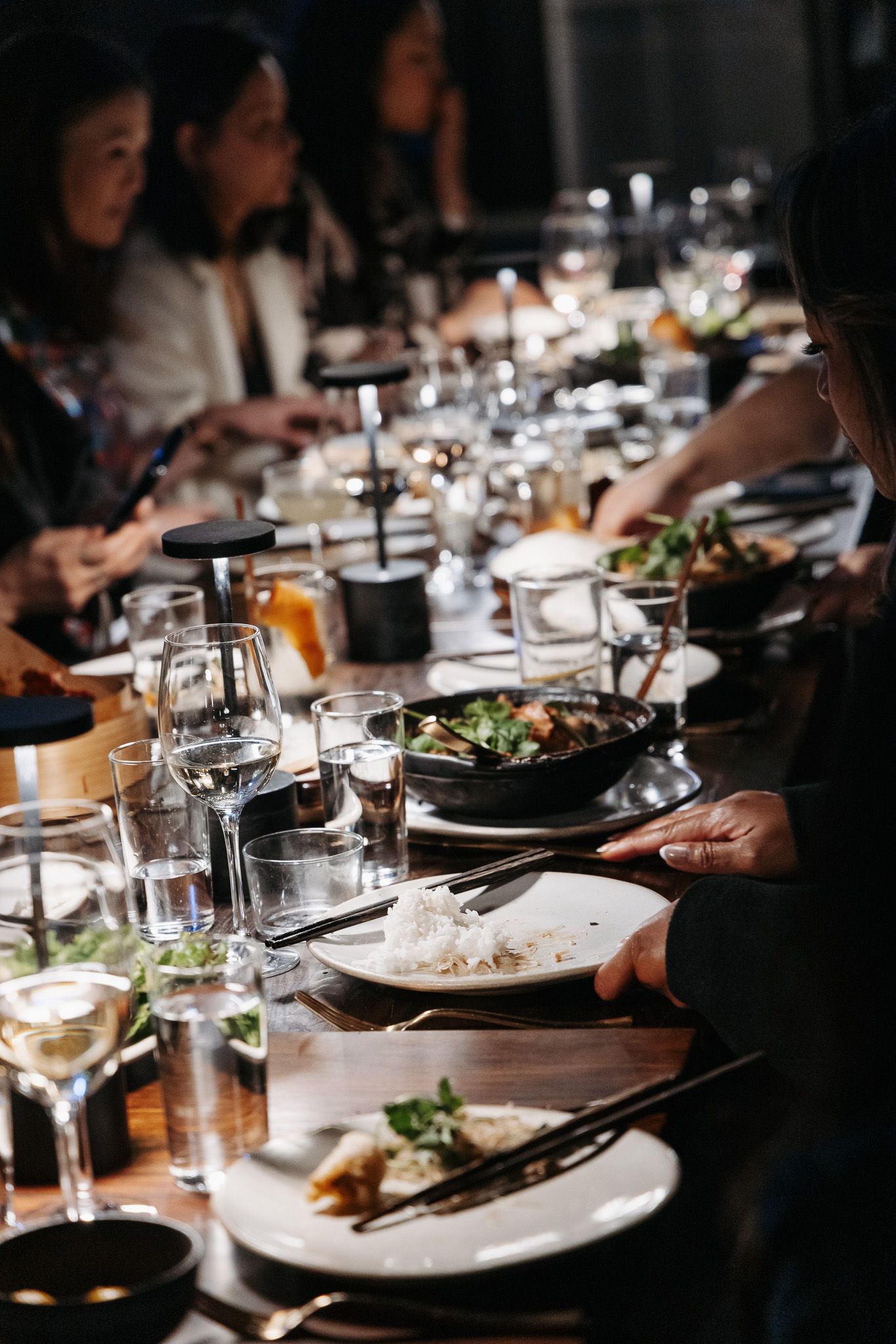 Elegant dinner table setting with multiple courses, wine glasses and ambient lighting.