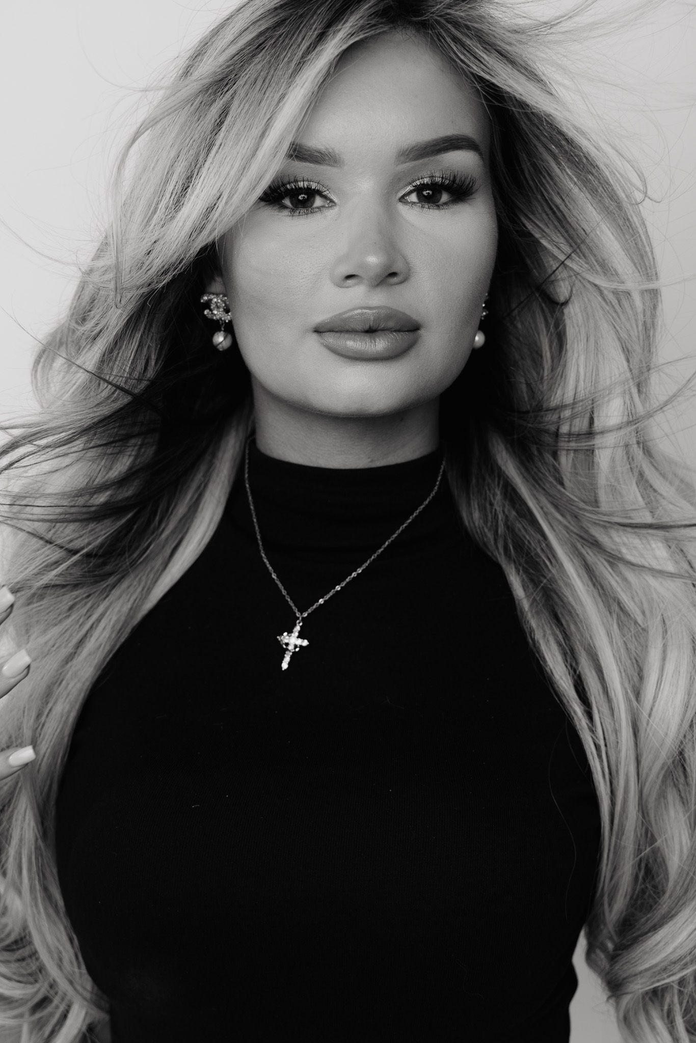 Black and white fashion portraits showcase glamorous blonde hair styling and dramatic makeup against dark turtleneck sweater.