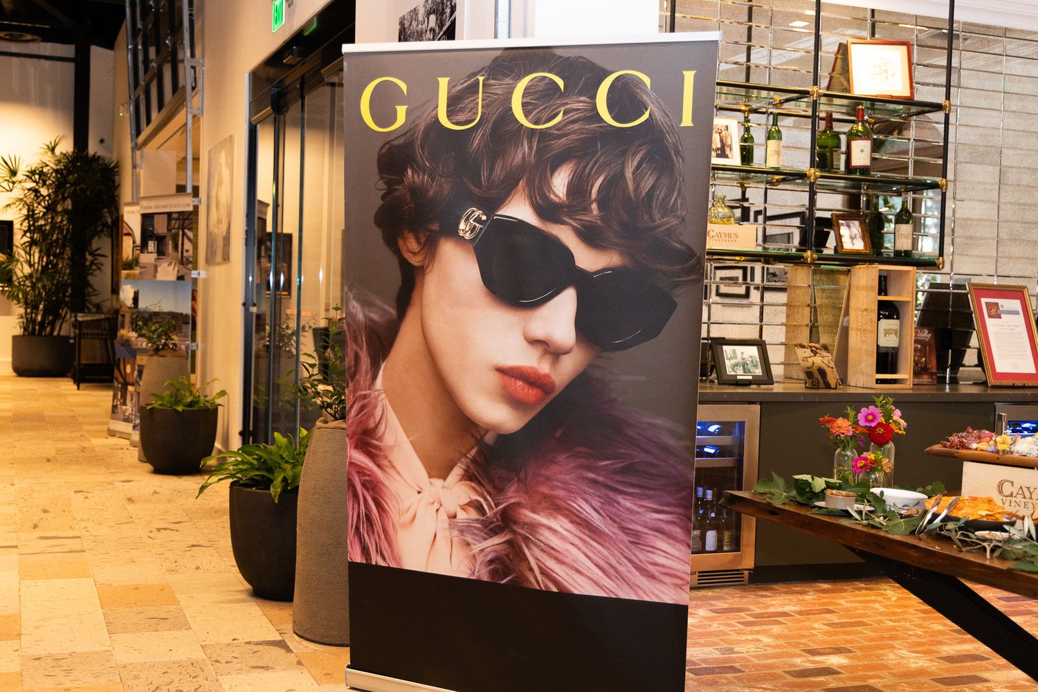 Luxury retail store interior with illuminated Gucci signage and fashion displays along a marble-floored hallway.