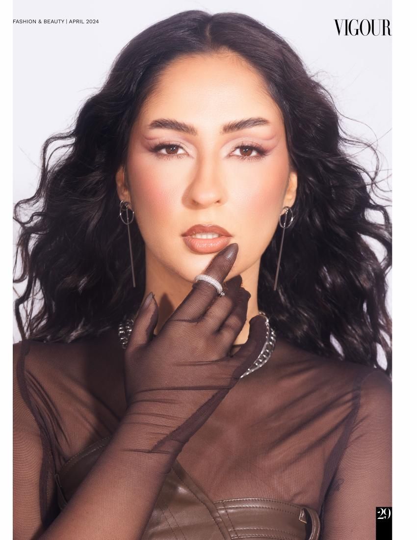 Glamour beauty portrait with long dark hair and sheer black gloves against neutral background.