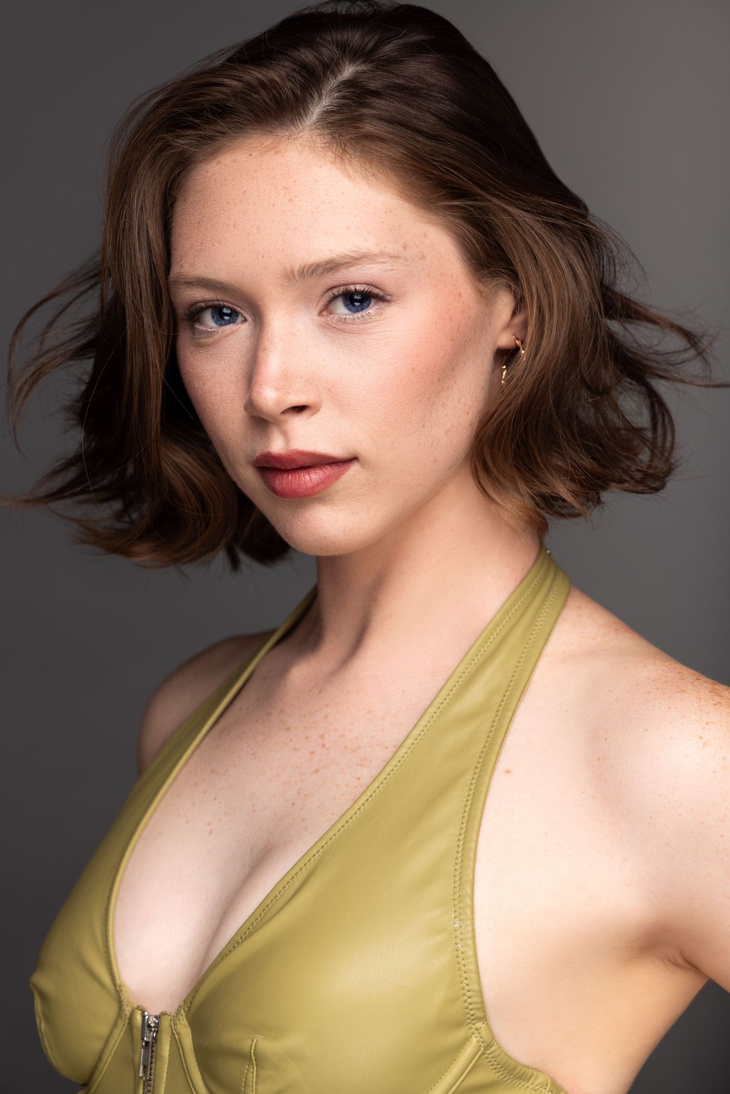 Fashion photo series showing model with brown wavy hair wearing olive green leather halter top against gray background.