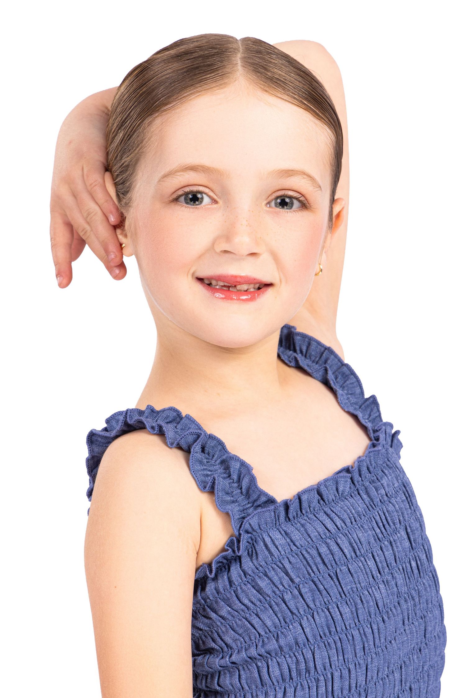 Child in navy blue ruched dress with ruffled neckline poses against white background in three similar portraits.