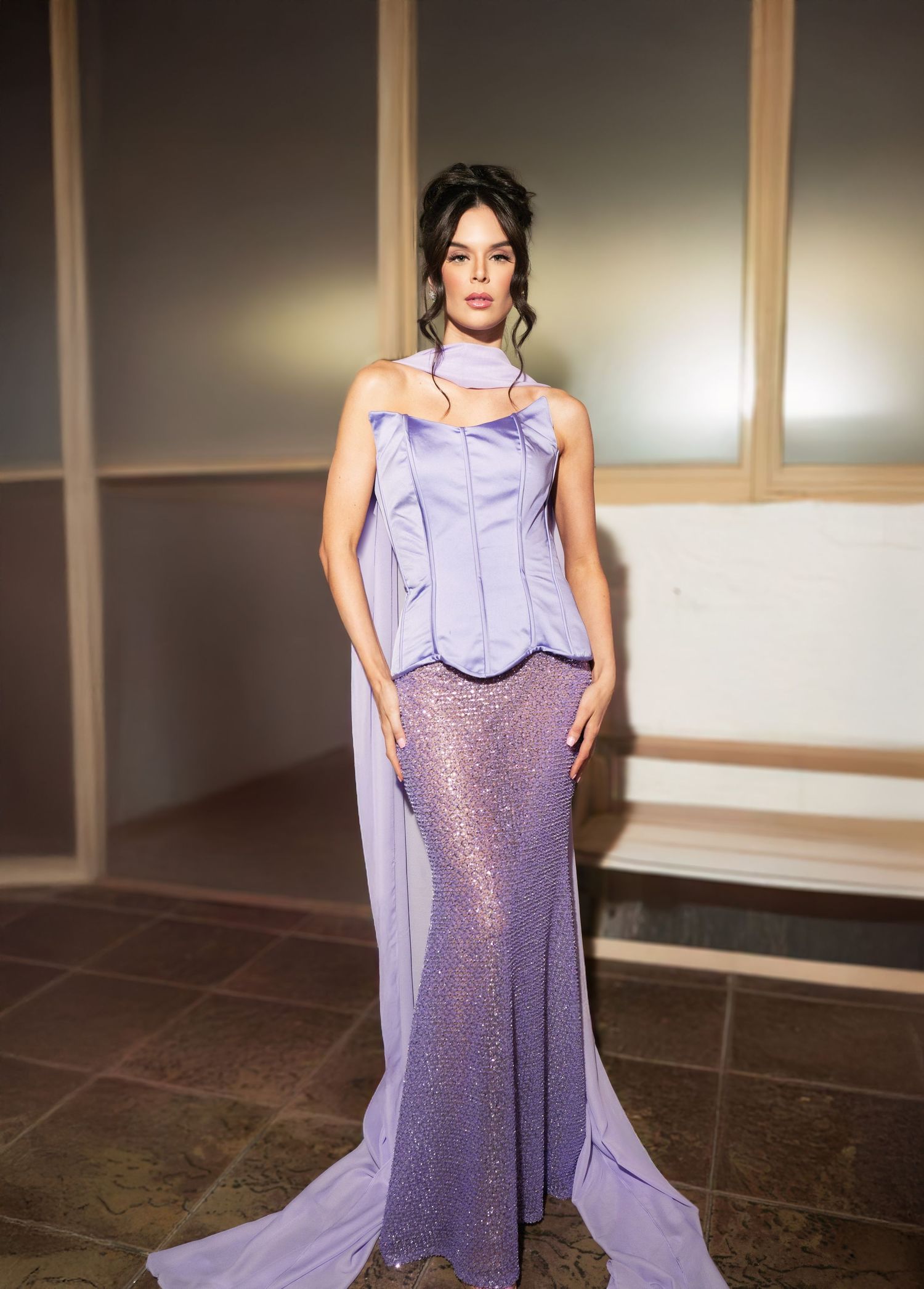 Model showcases flowing lavender gown with sequin details on dark tile floor.