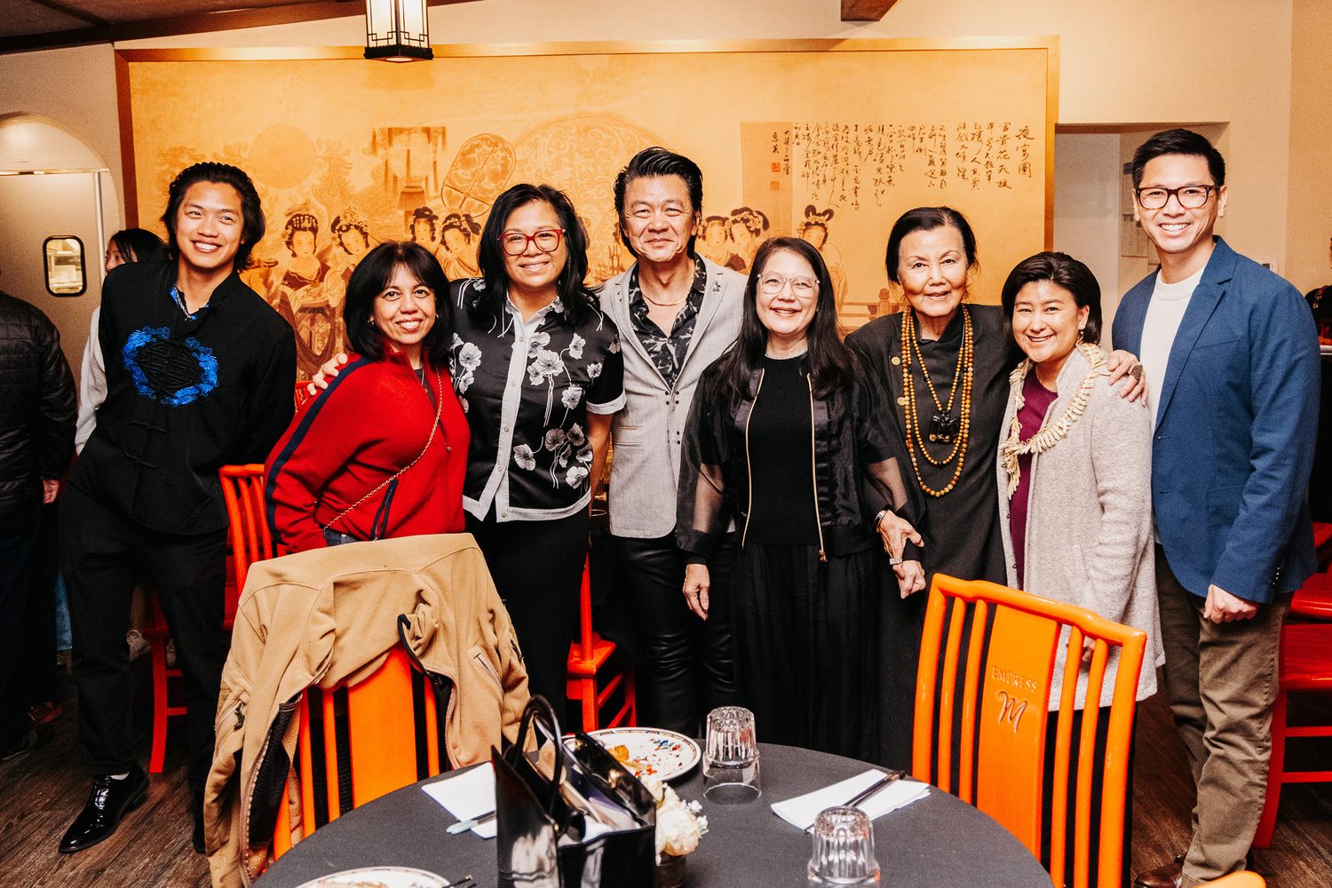 Large group of people gathered at an indoor social event with warm lighting and traditional Asian decor.