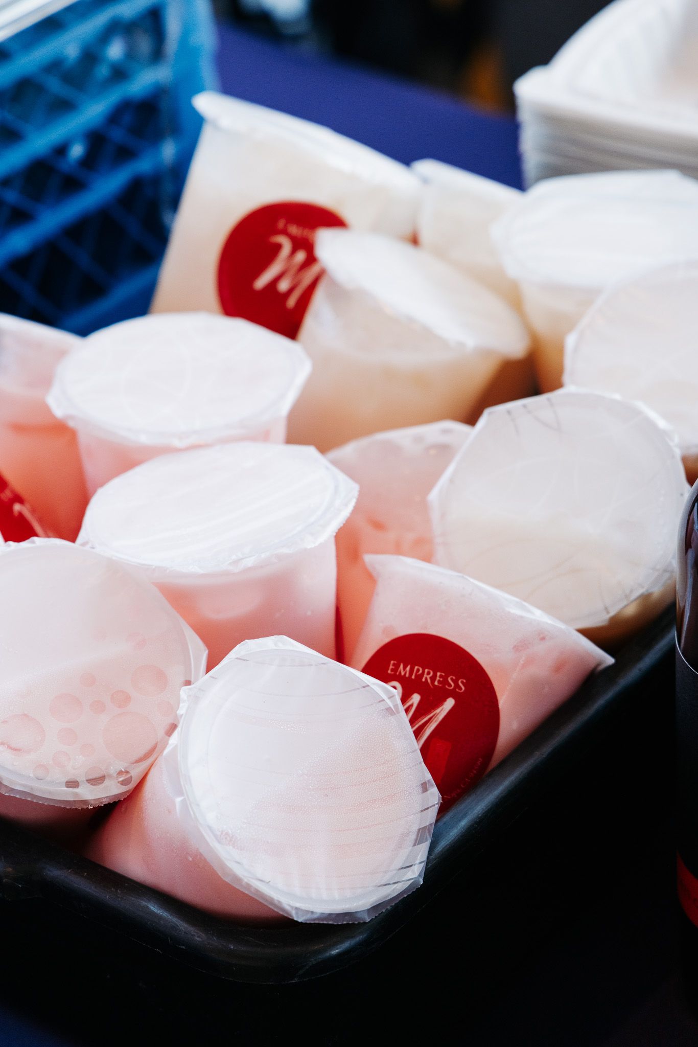 White plastic sauce containers with red lids arranged in a blue serving tray.