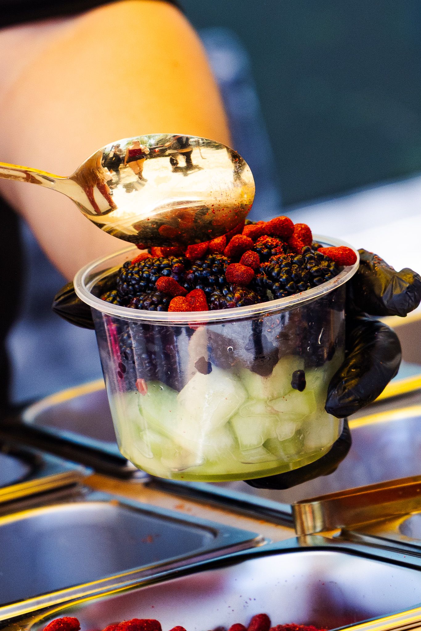 Fresh fruit cup with blackberries and raspberries being served with gold spoon.