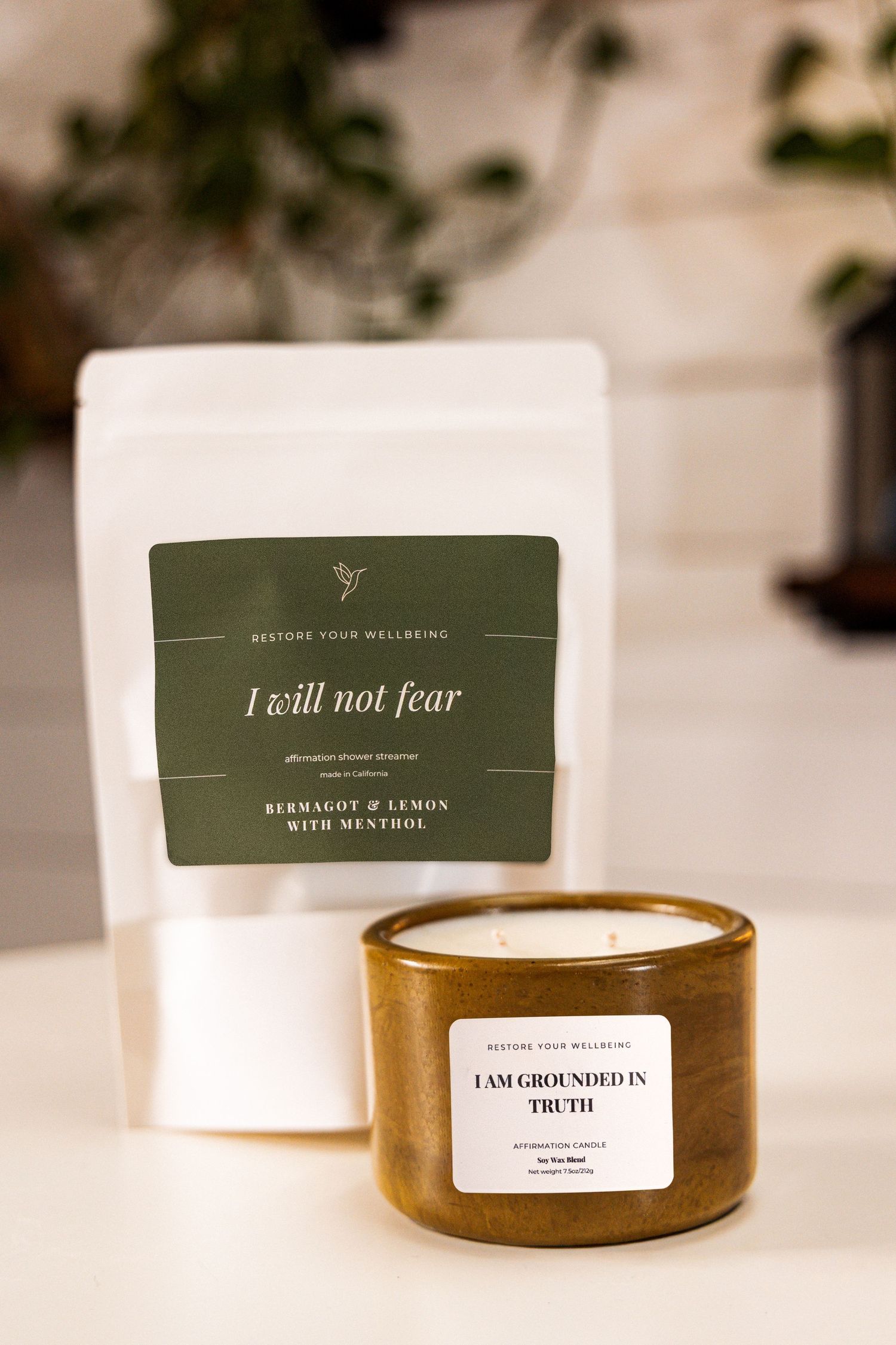 White candles with minimalist green and white labels displayed in a row on a light surface.