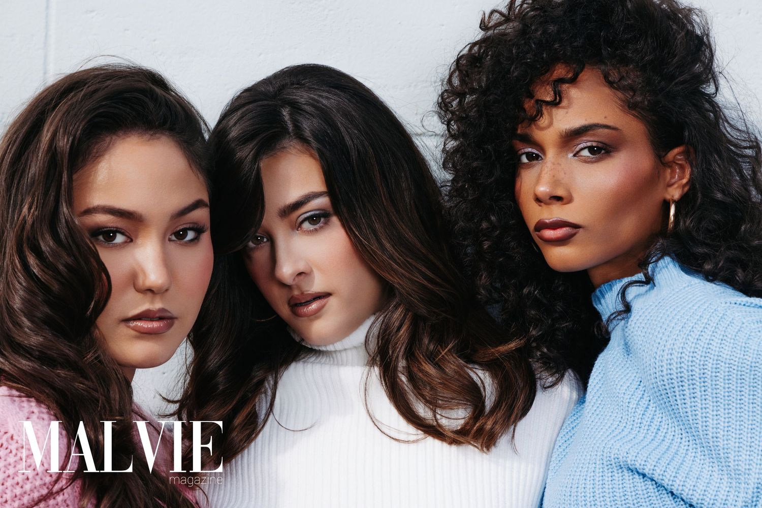 Three diverse women pose together for MALVIE magazine, wearing stylish tops in a professional fashion editorial shoot.