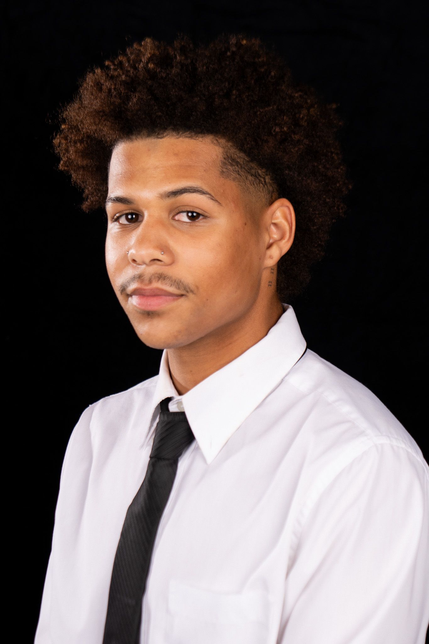 School photos showing different expressions while wearing a white shirt and black tie against a dark backdrop.