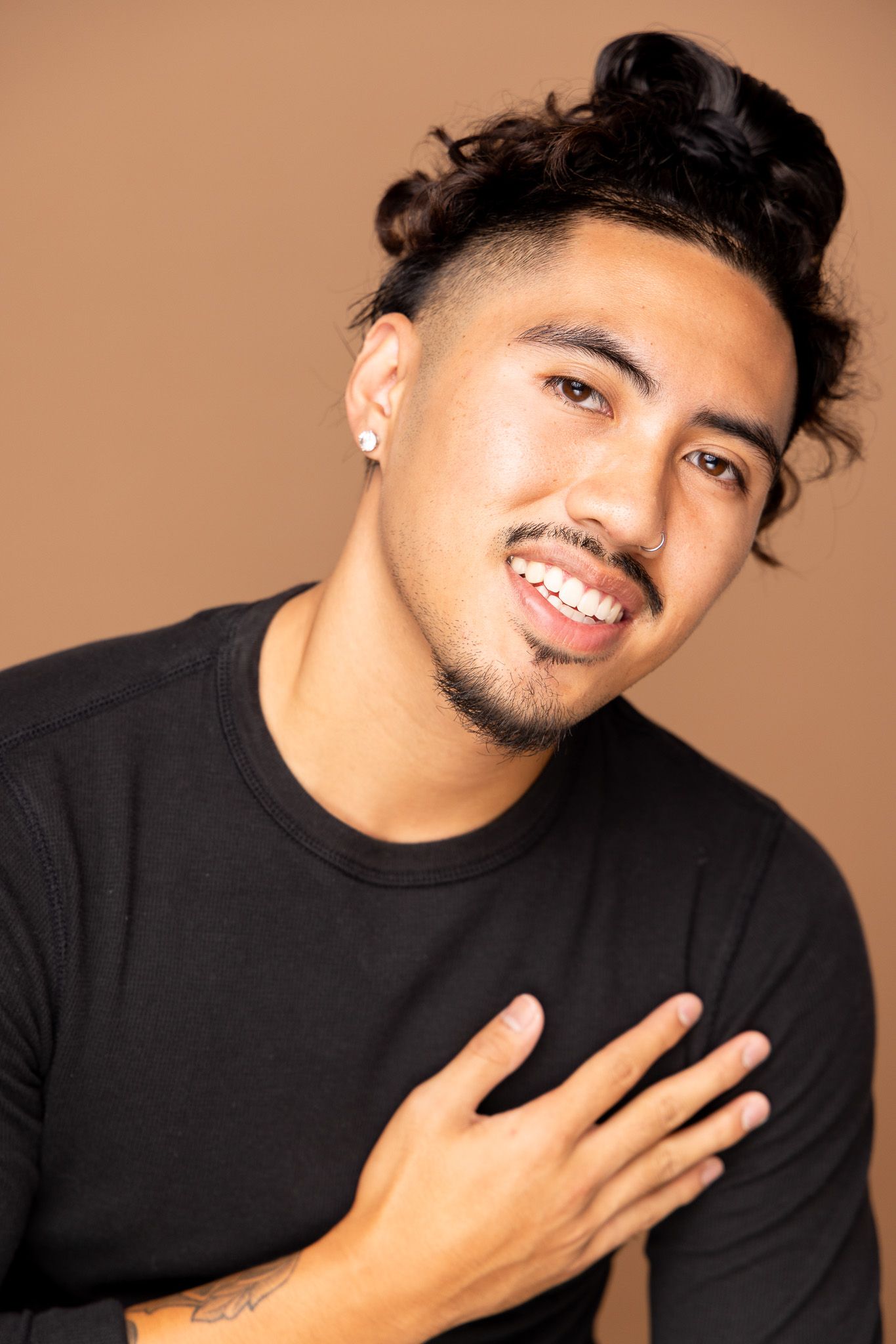 Expressive portraits in black shirt against brown background.