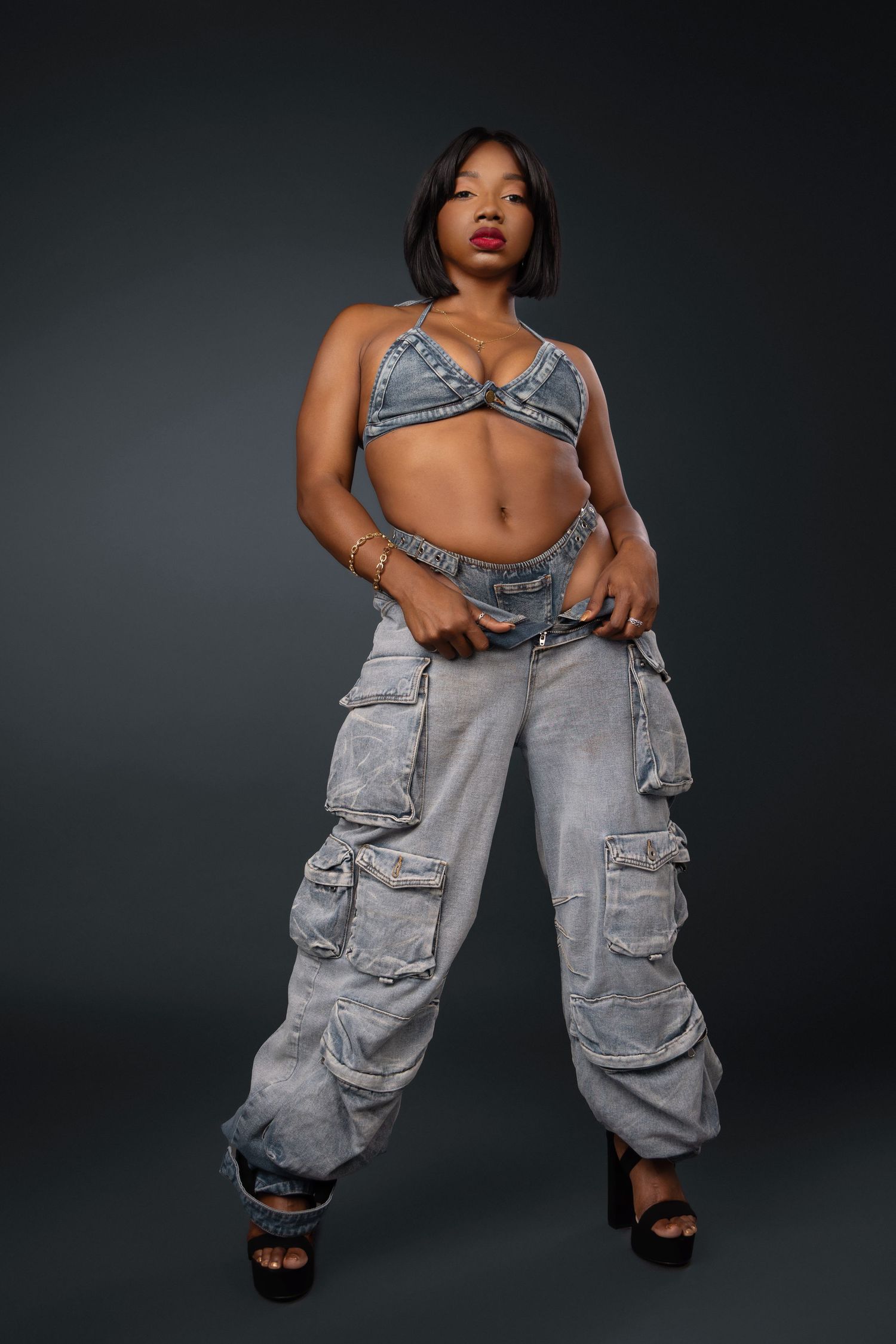 Fashion model wearing oversized gray cargo pants and black slides poses in dynamic editorial style shots against dark backdrop.