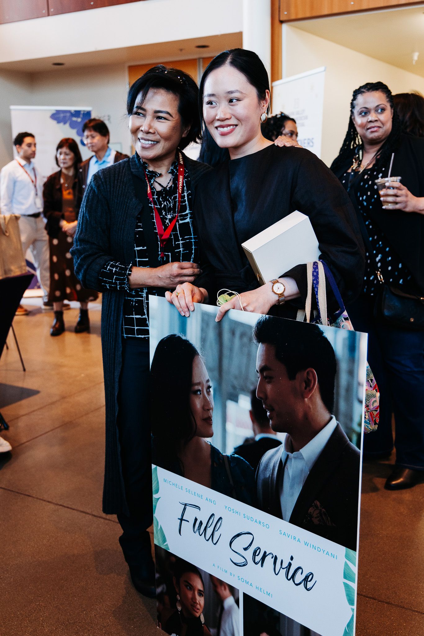 Staff members in black attire holding service signs at a catering event.