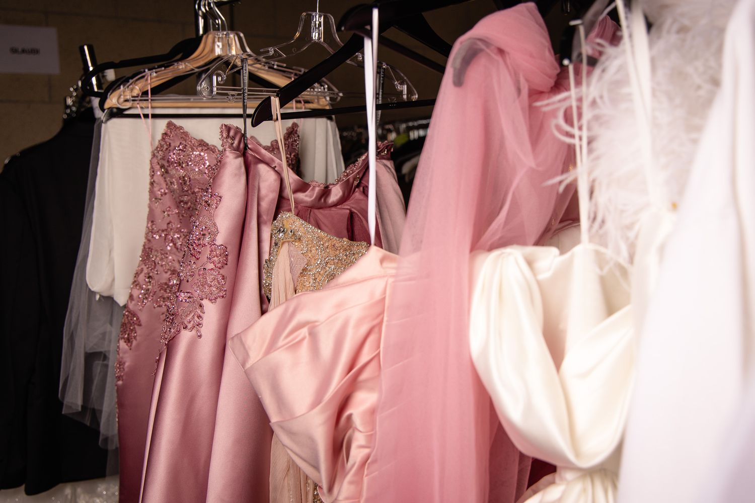 Rack of pink and white formal dresses hanging in a fashion wardrobe.