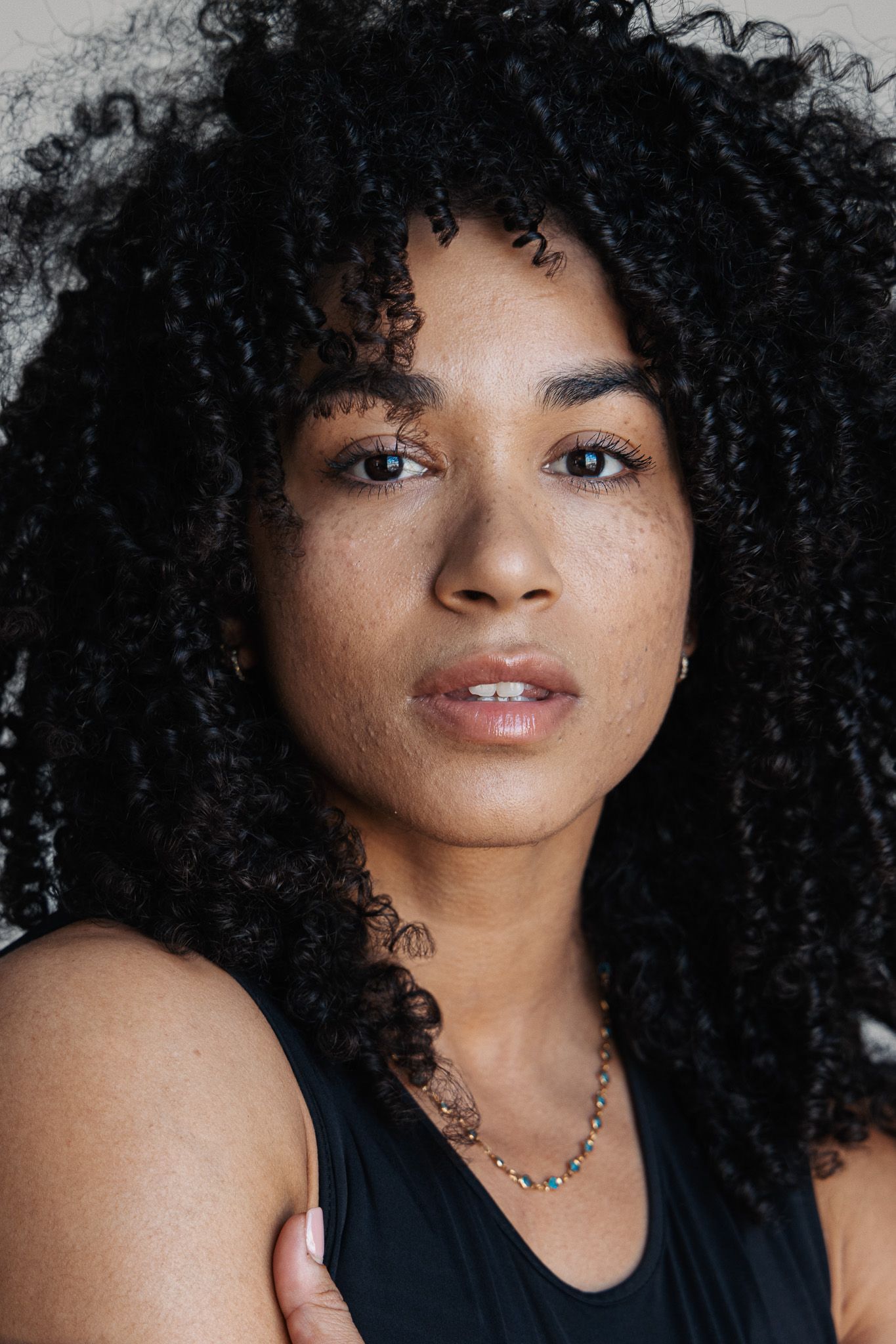 Portrait series showing different angles of a person with voluminous natural curly black hair against a light background.
