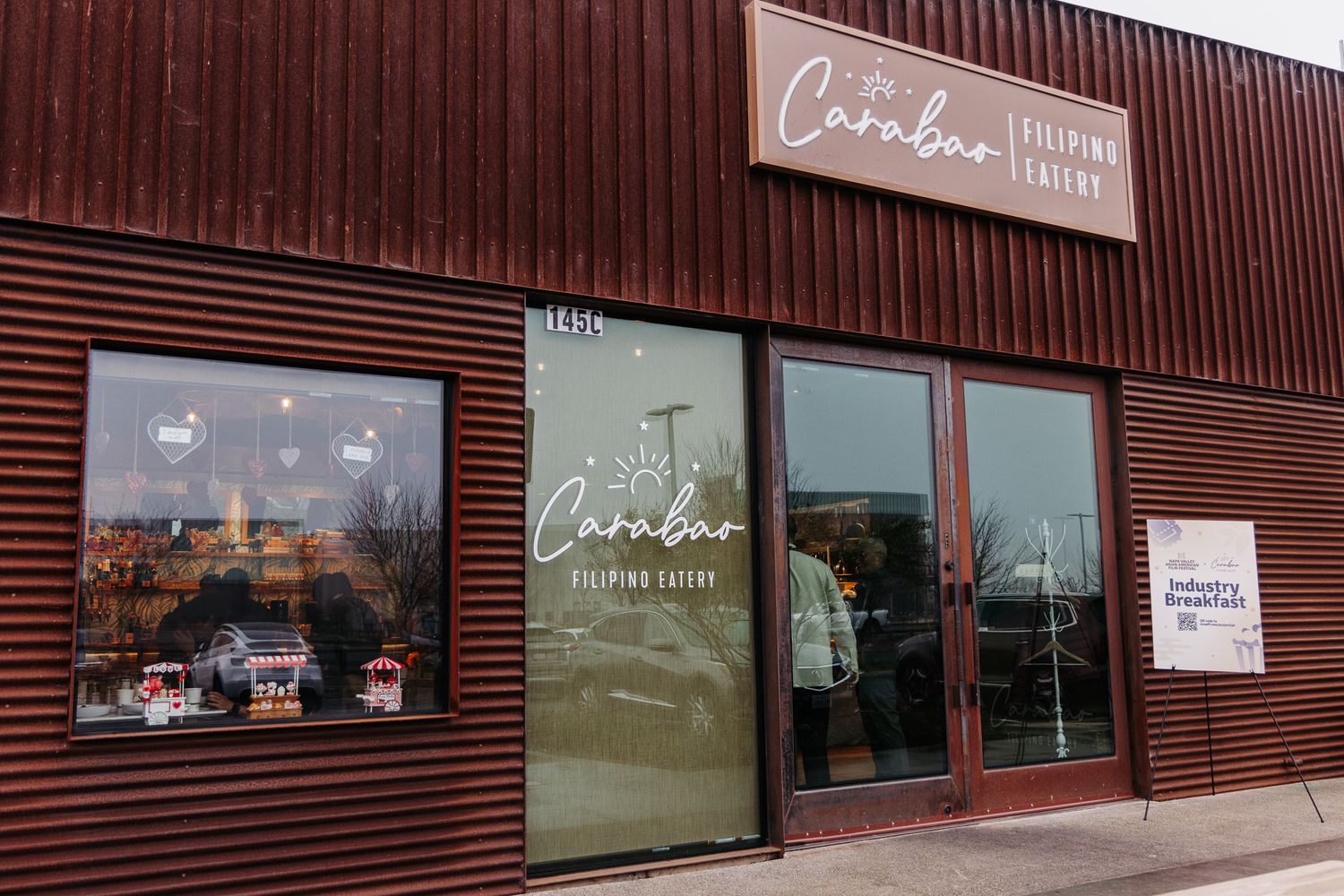 A brown exterior storefront of Caribou Coffee shop with a window display and glass entrance door.