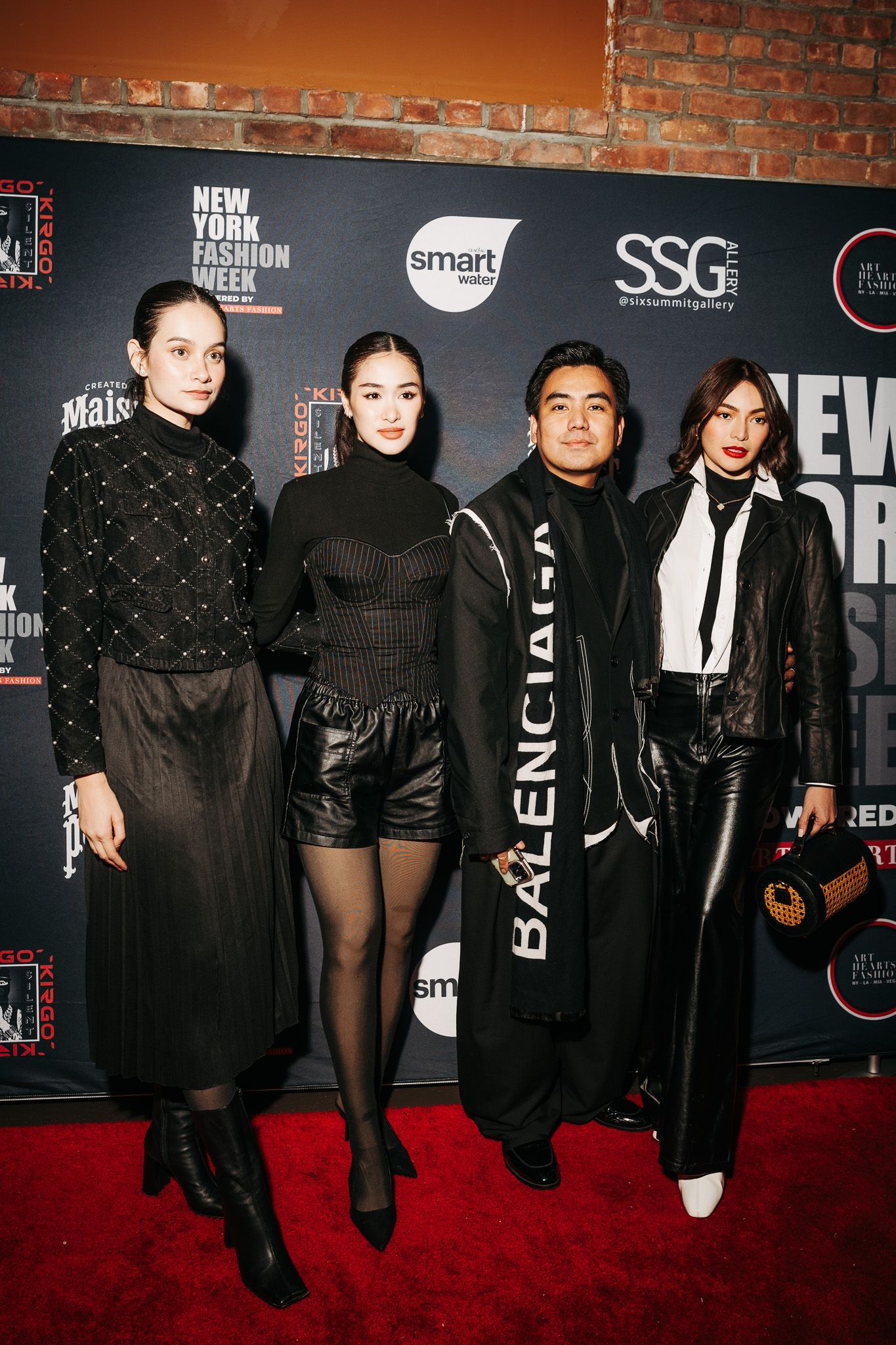 Four stylish guests pose on the red carpet at New York Fashion Week wearing black and white evening attire.