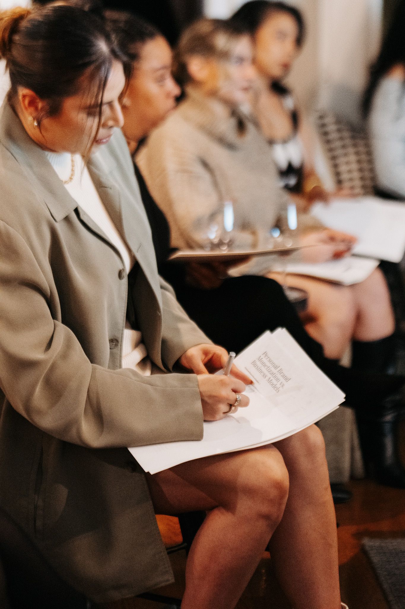 Women seated in professional attire taking notes during a meeting.