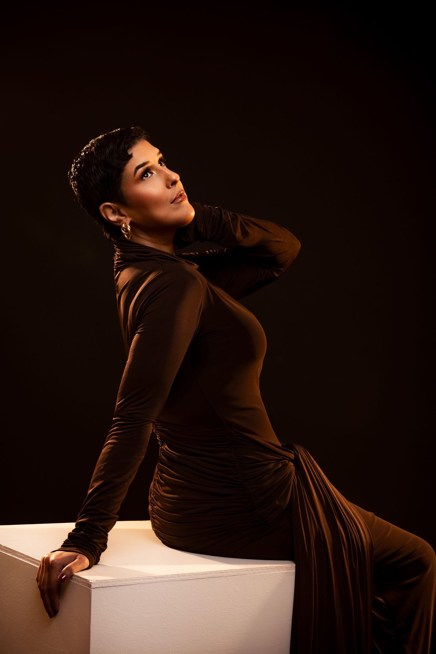 A dramatic series of photos showing someone in a dark brown velvet dress posing artistically on a white surface.