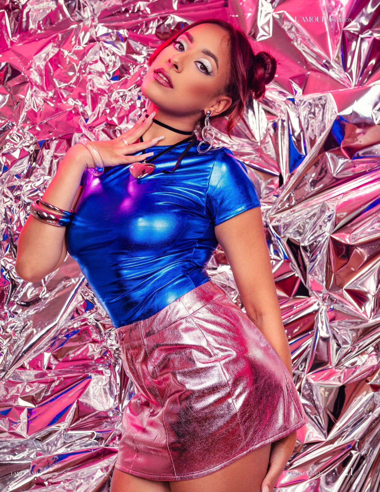 Fashion model poses on metallic pink and silver foil backdrop wearing electric blue metallic dress.
